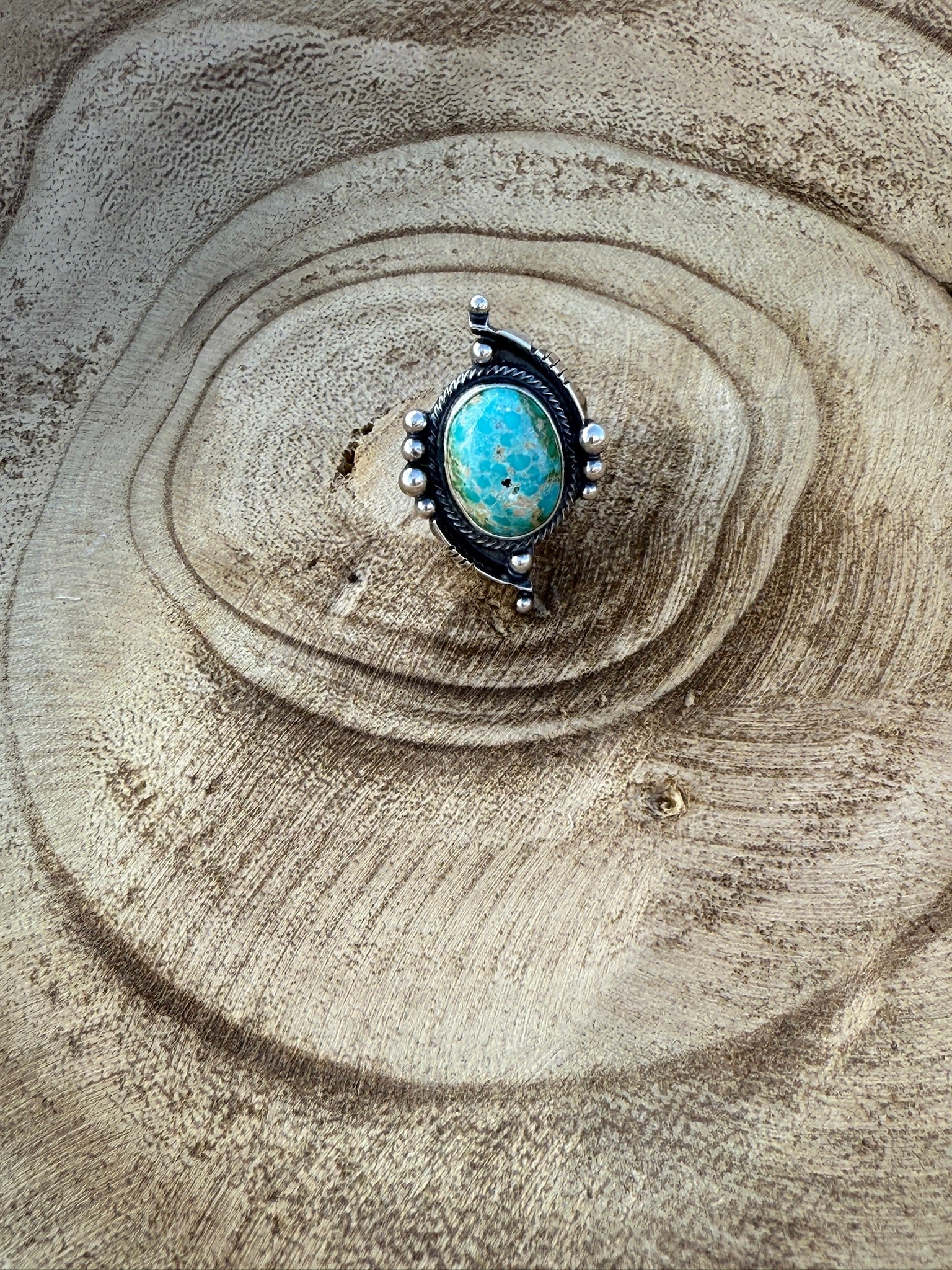 Turquoise ring with silver accents on a textured stone surface