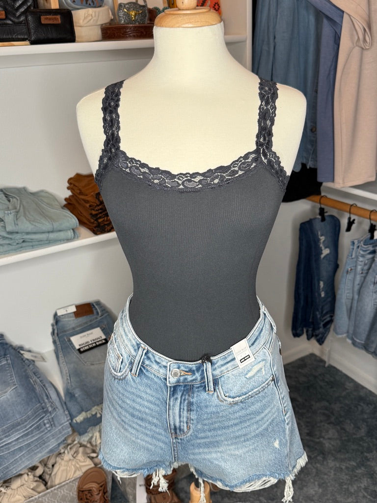 A mannequin displaying a gray lace-trim tank top with spaghetti straps, paired with blue denim shorts.