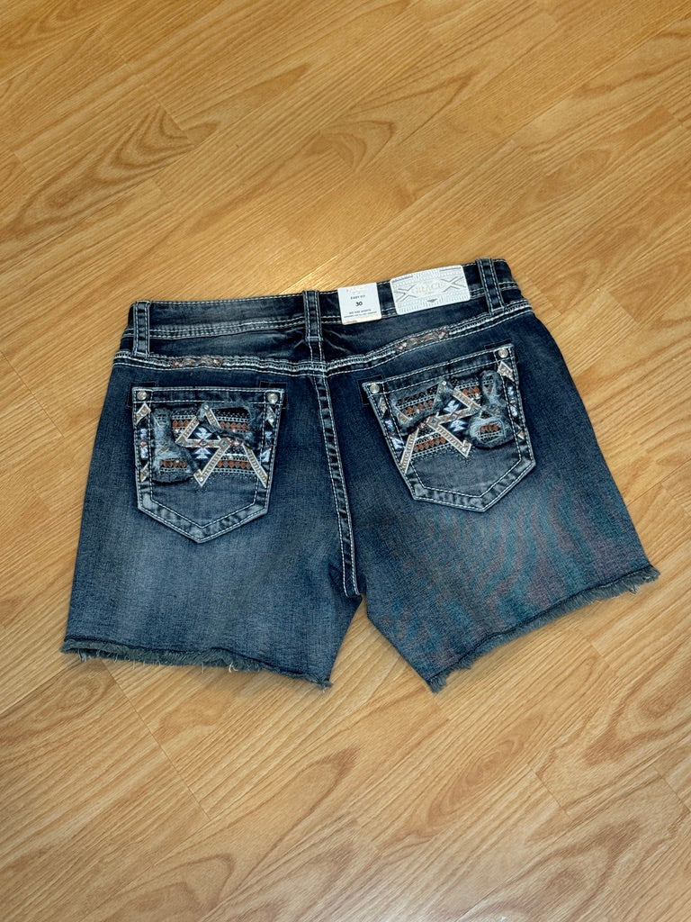 Blue denim shorts with decorative pockets on a wooden floor
