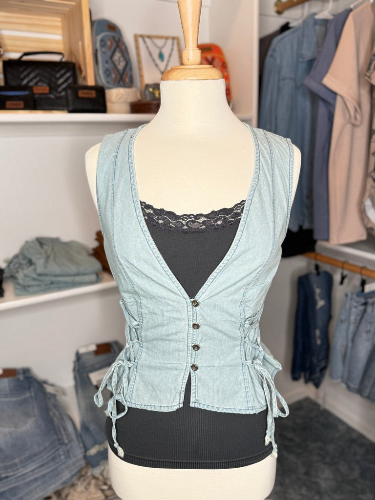A lightweight denim vest with drawstring detail displayed on a mannequin, layered over a black top.