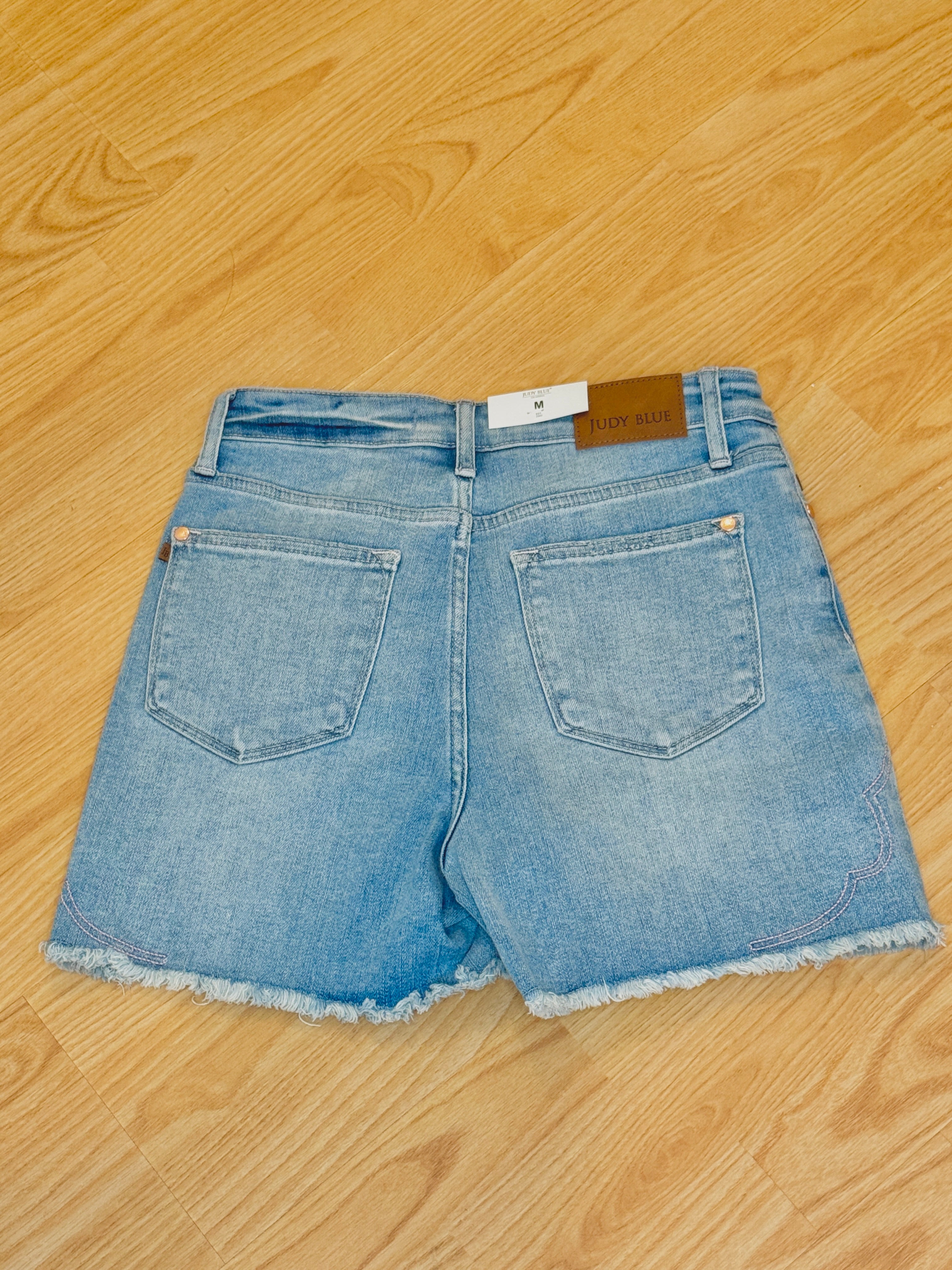 Back view of denim shorts on a wooden floor.