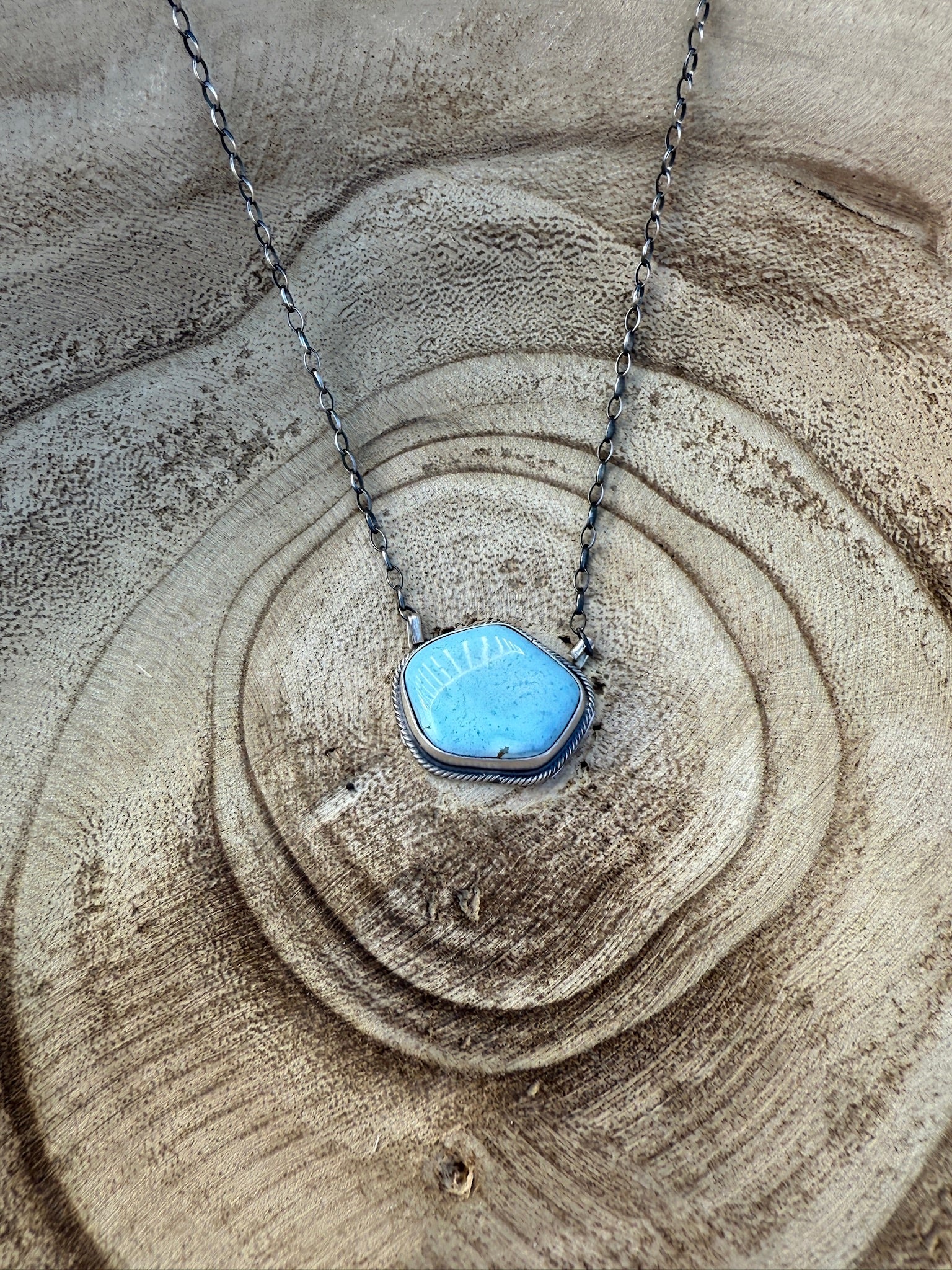 Necklace with a blue pendant on a sandy surface