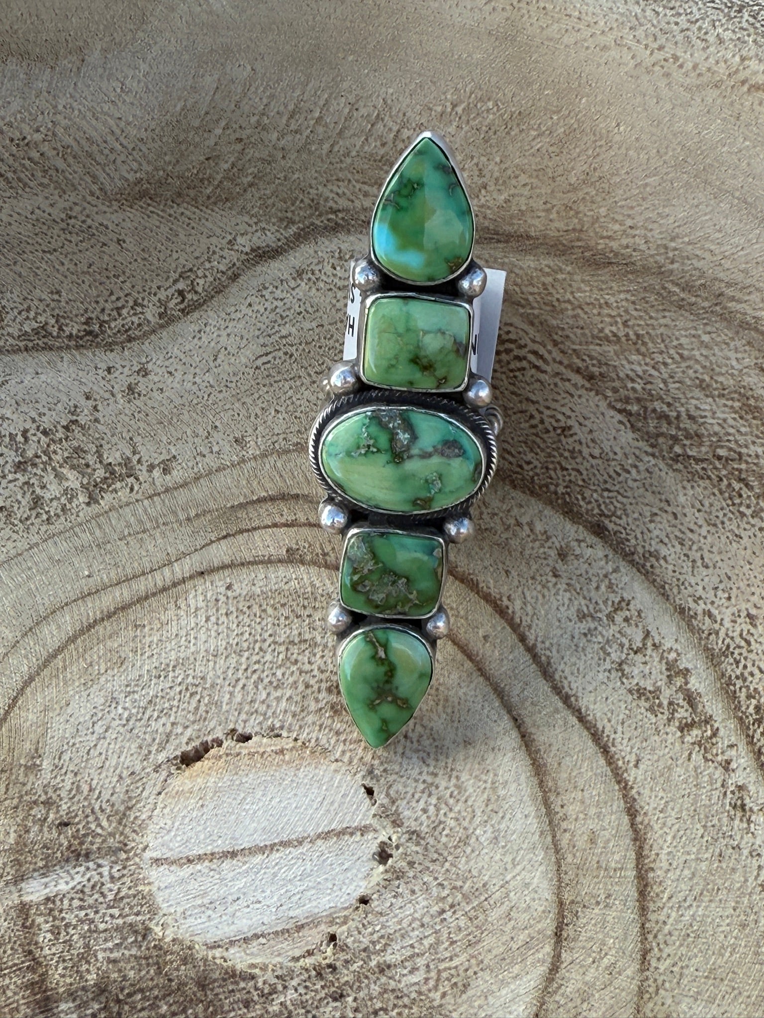Green stone and silver pendant on a textured beige background
