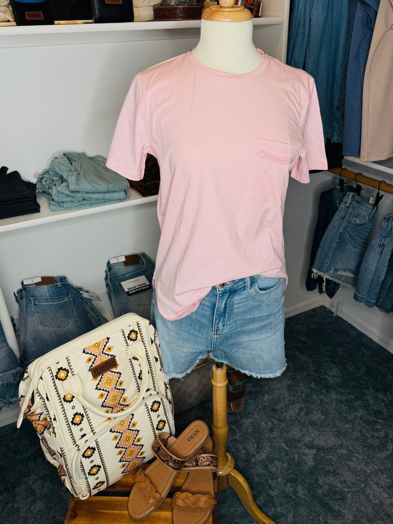 Mannequin wearing a pink t-shirt and denim shorts with a backpack and boots in a store setting.