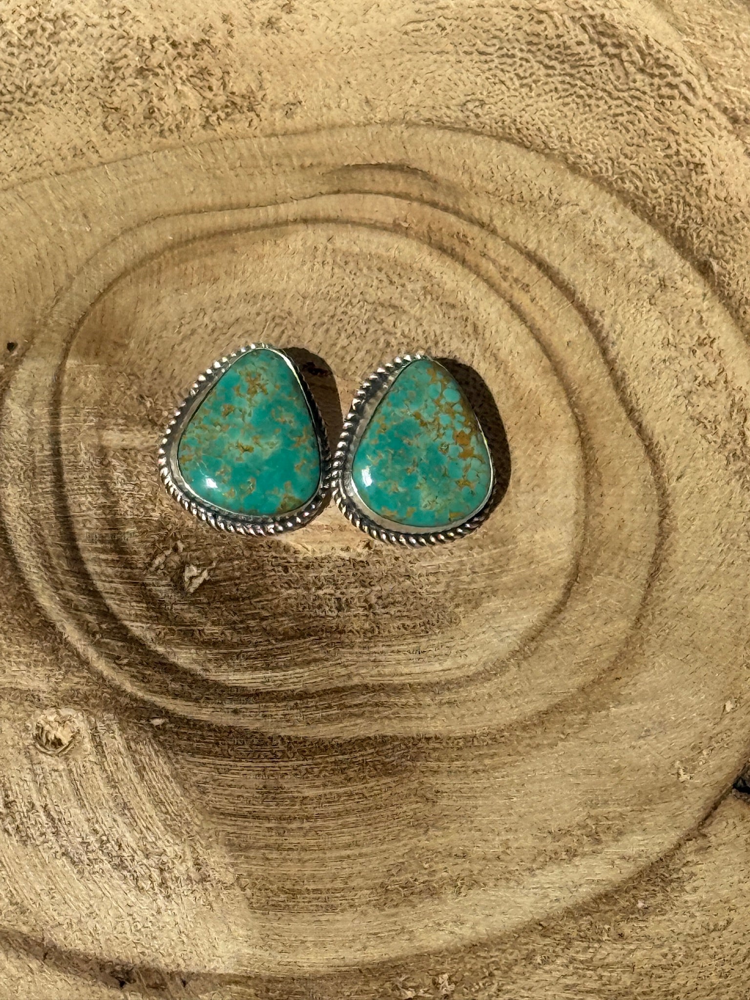 Turquoise stone earrings on a wooden surface