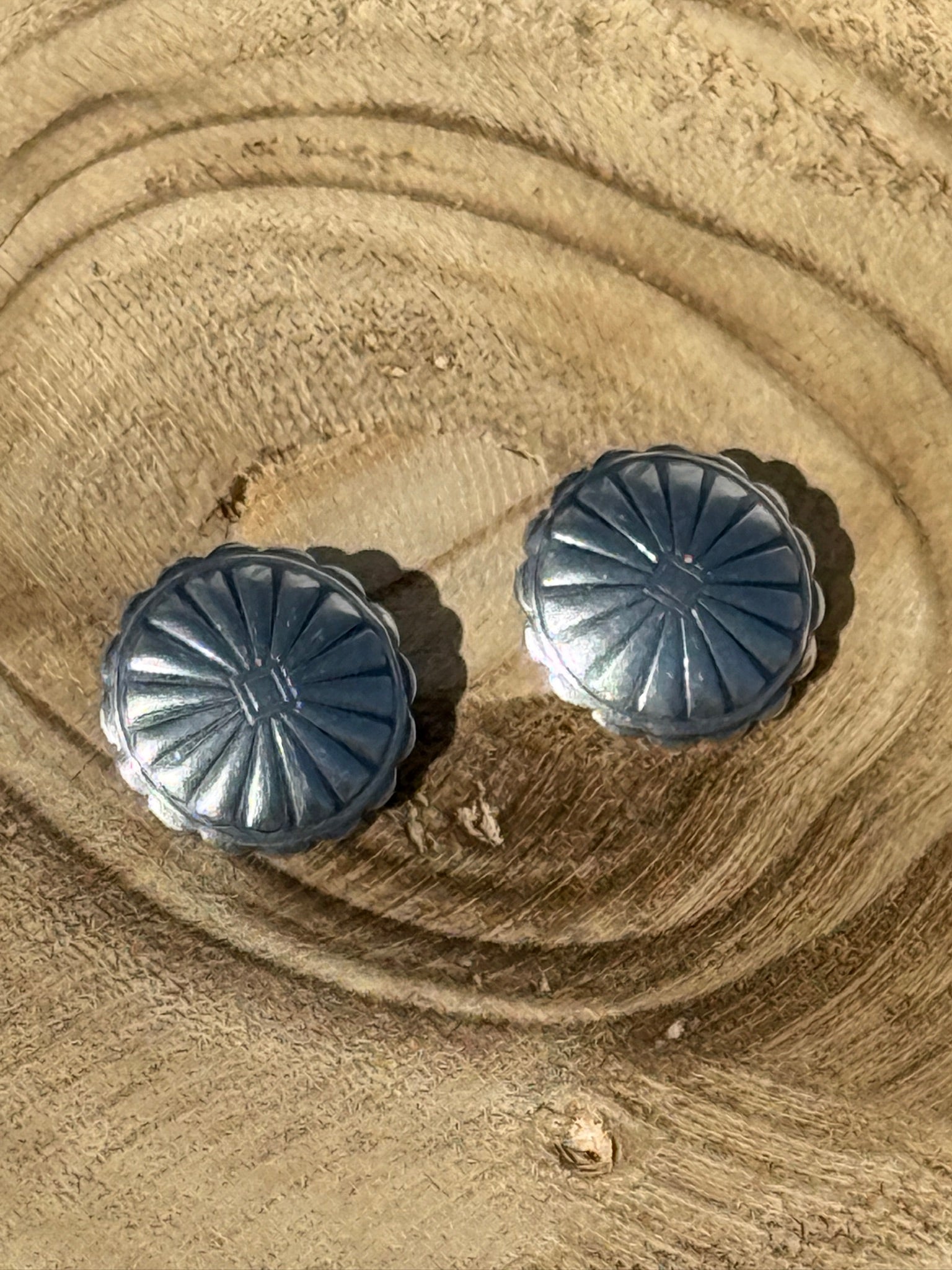 Pair of silver earrings on a sandy surface