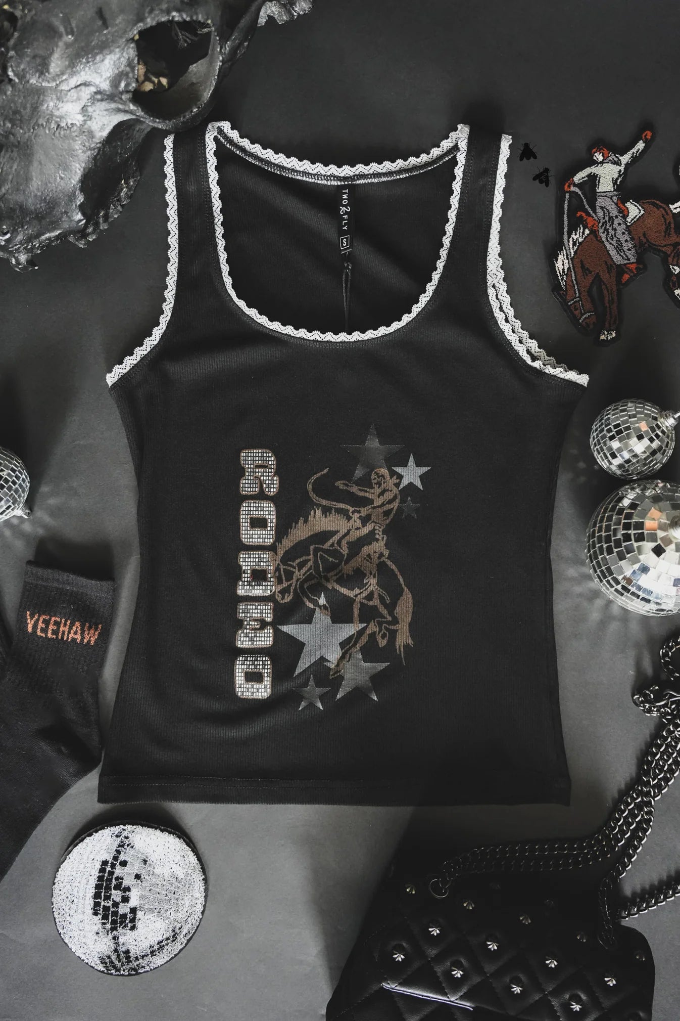 Black tank top with lace details on a dark background with decorative items.