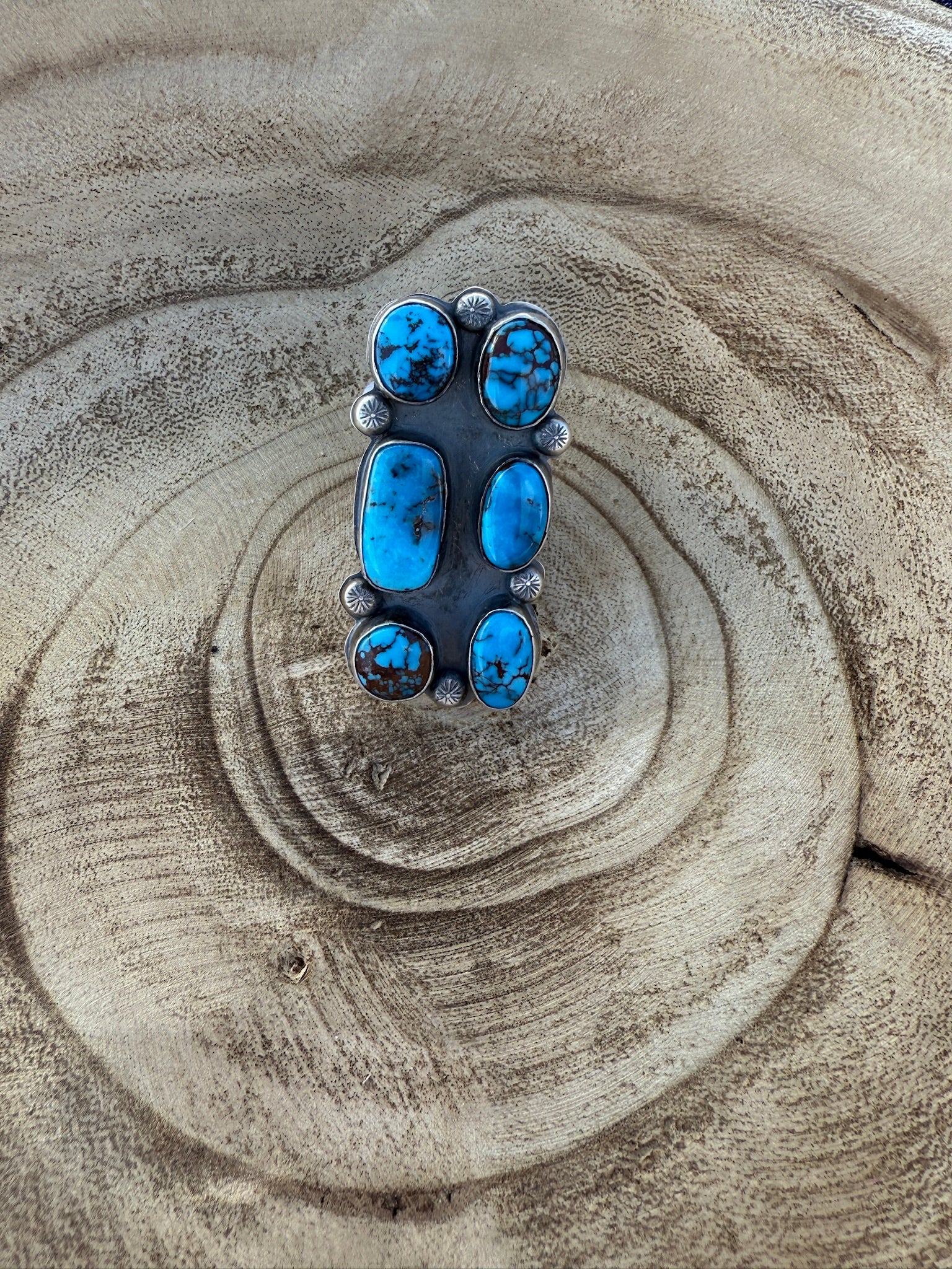 Silver ring with blue stones on a textured beige surface