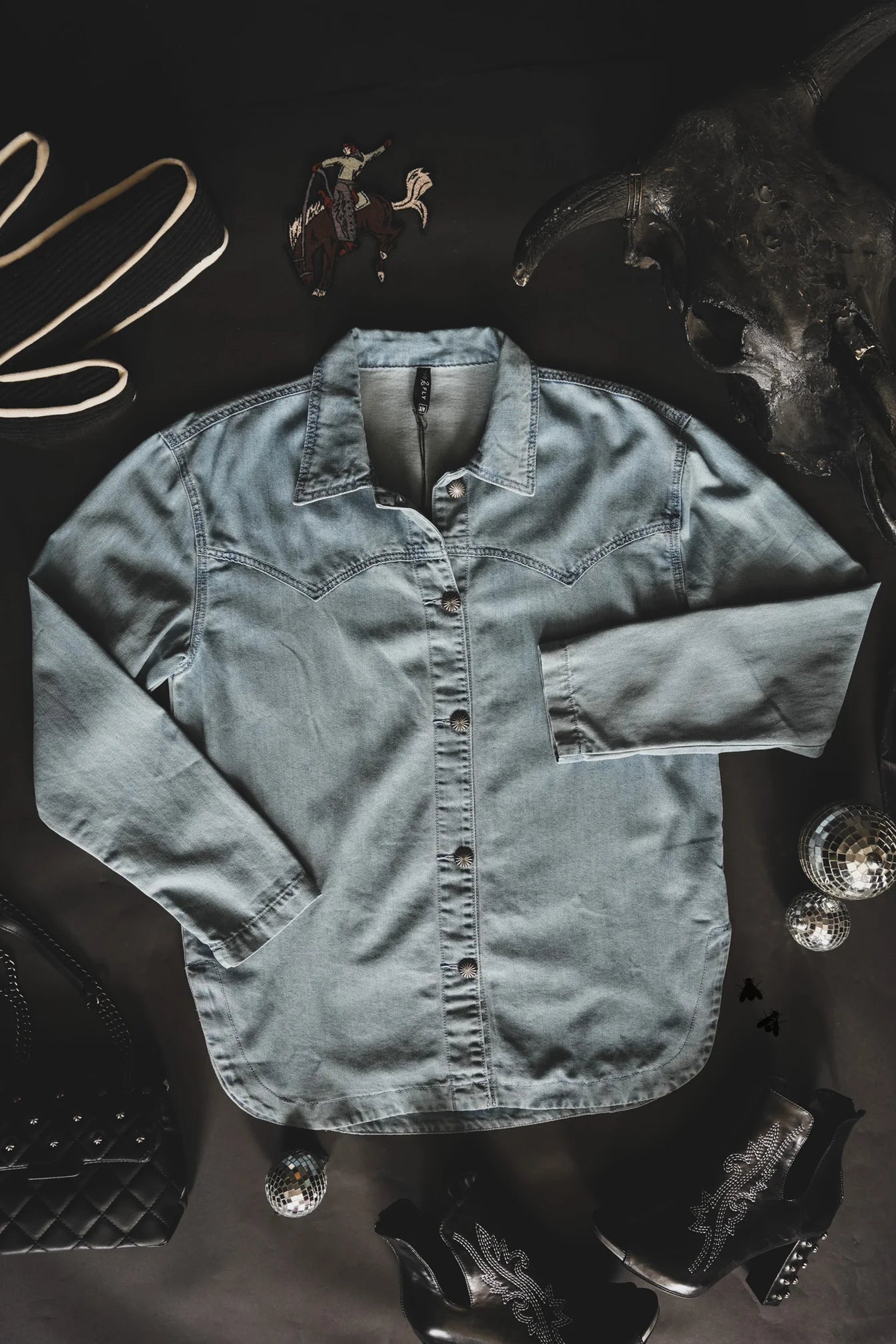 Light blue denim shirt on a dark background with abstract elements.