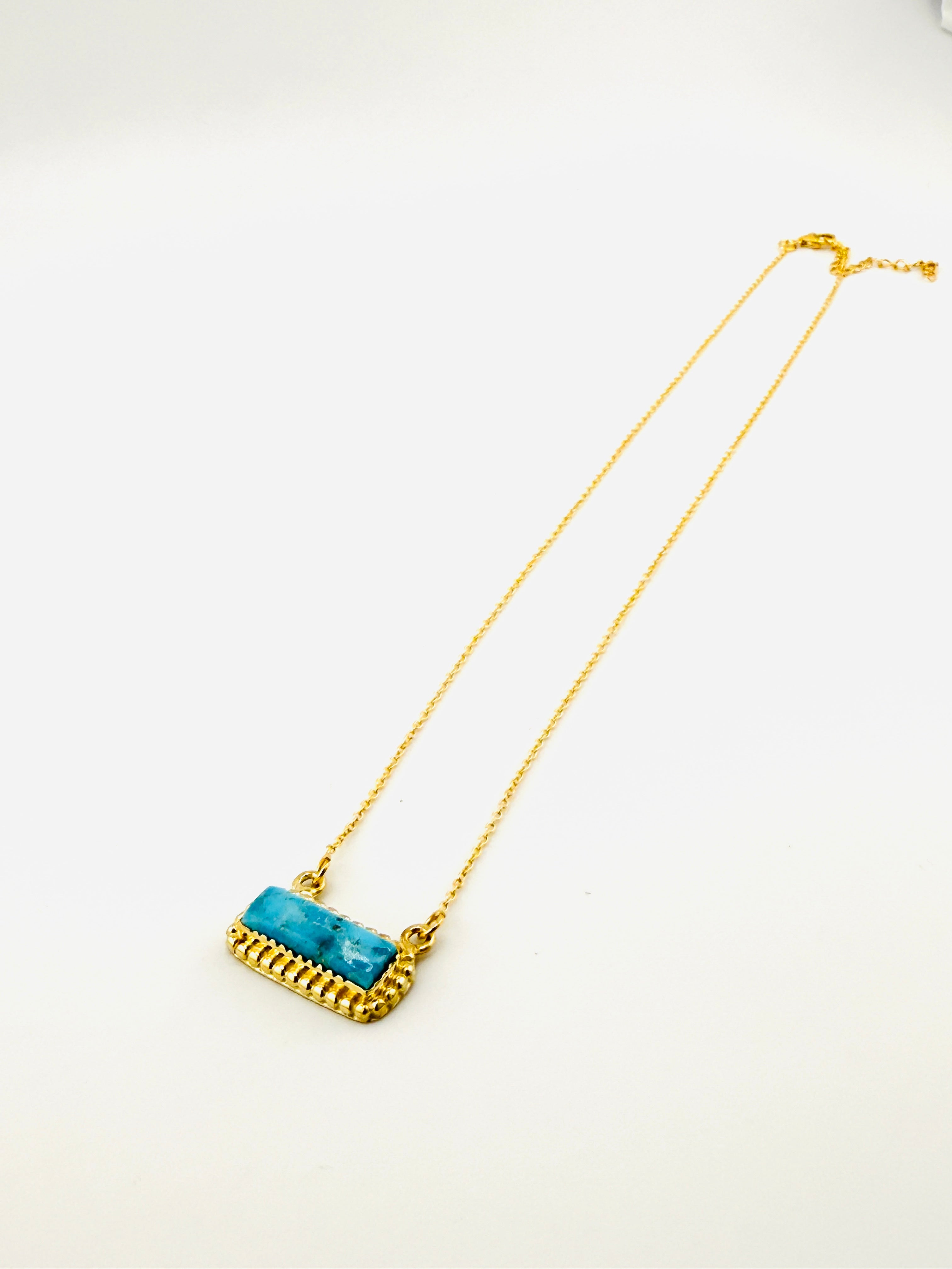 Gold necklace with a blue stone on a white background