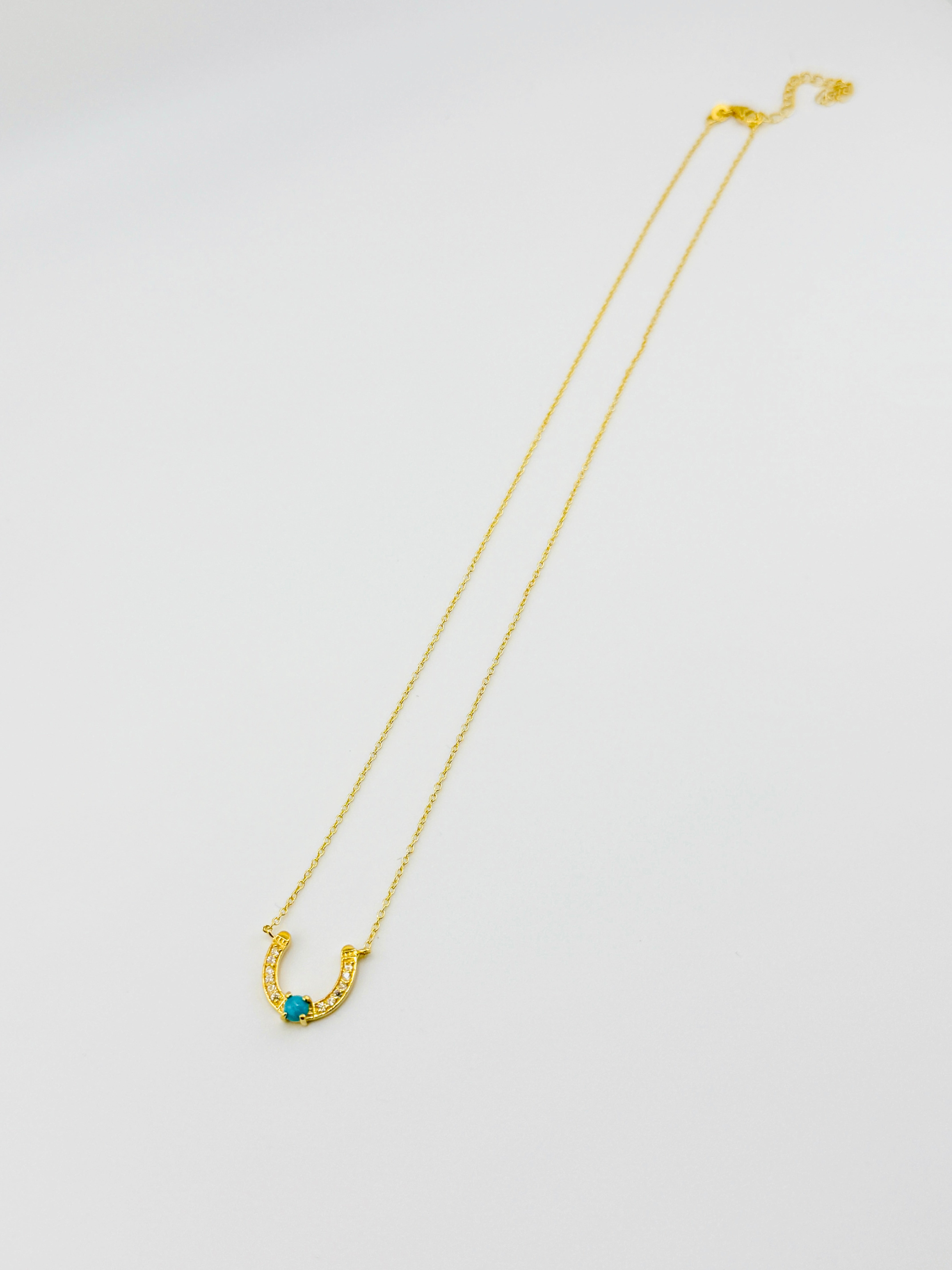 Gold necklace with a blue gemstone on a white background