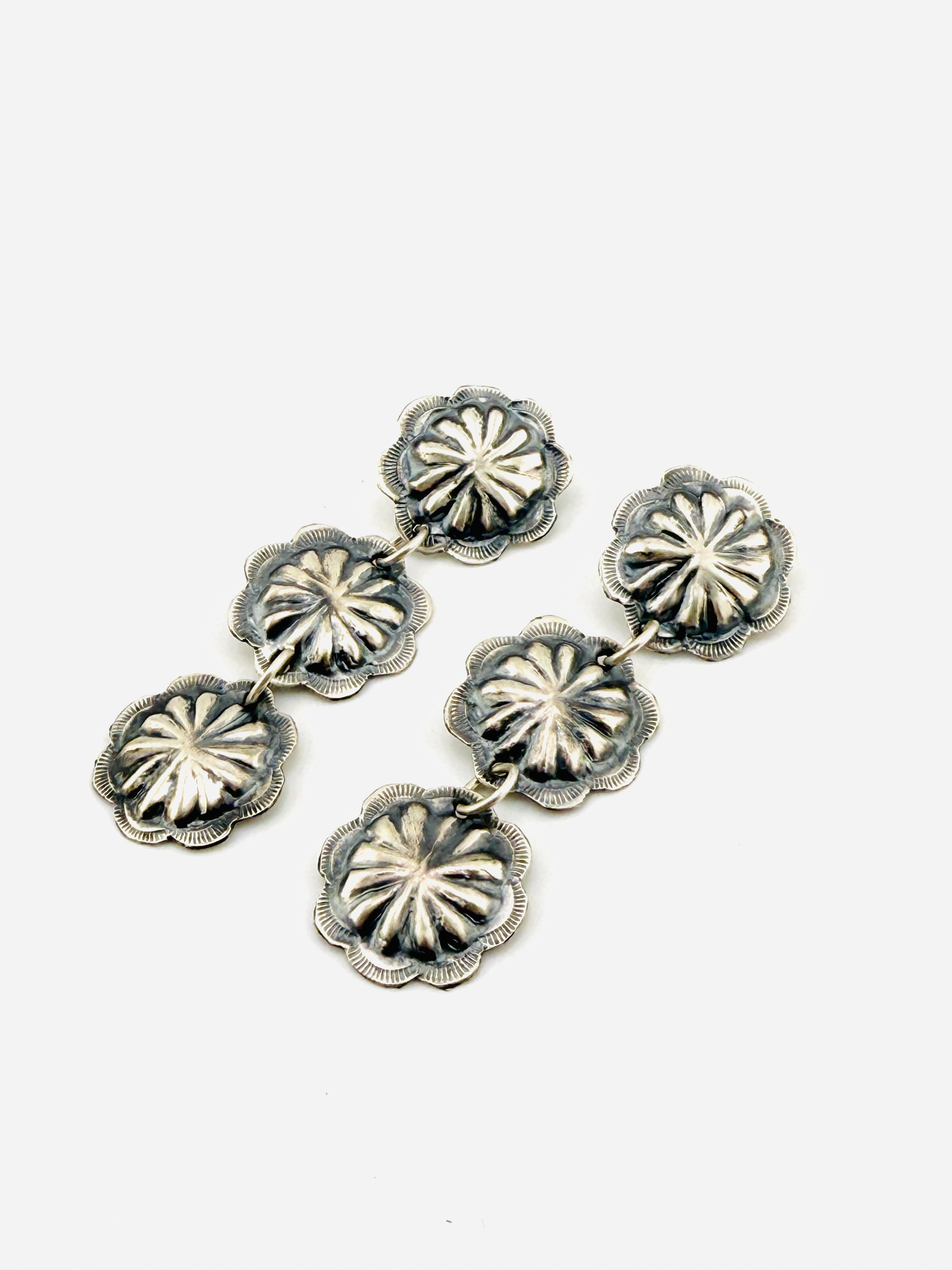 Silver floral concho style earrings on a white background
