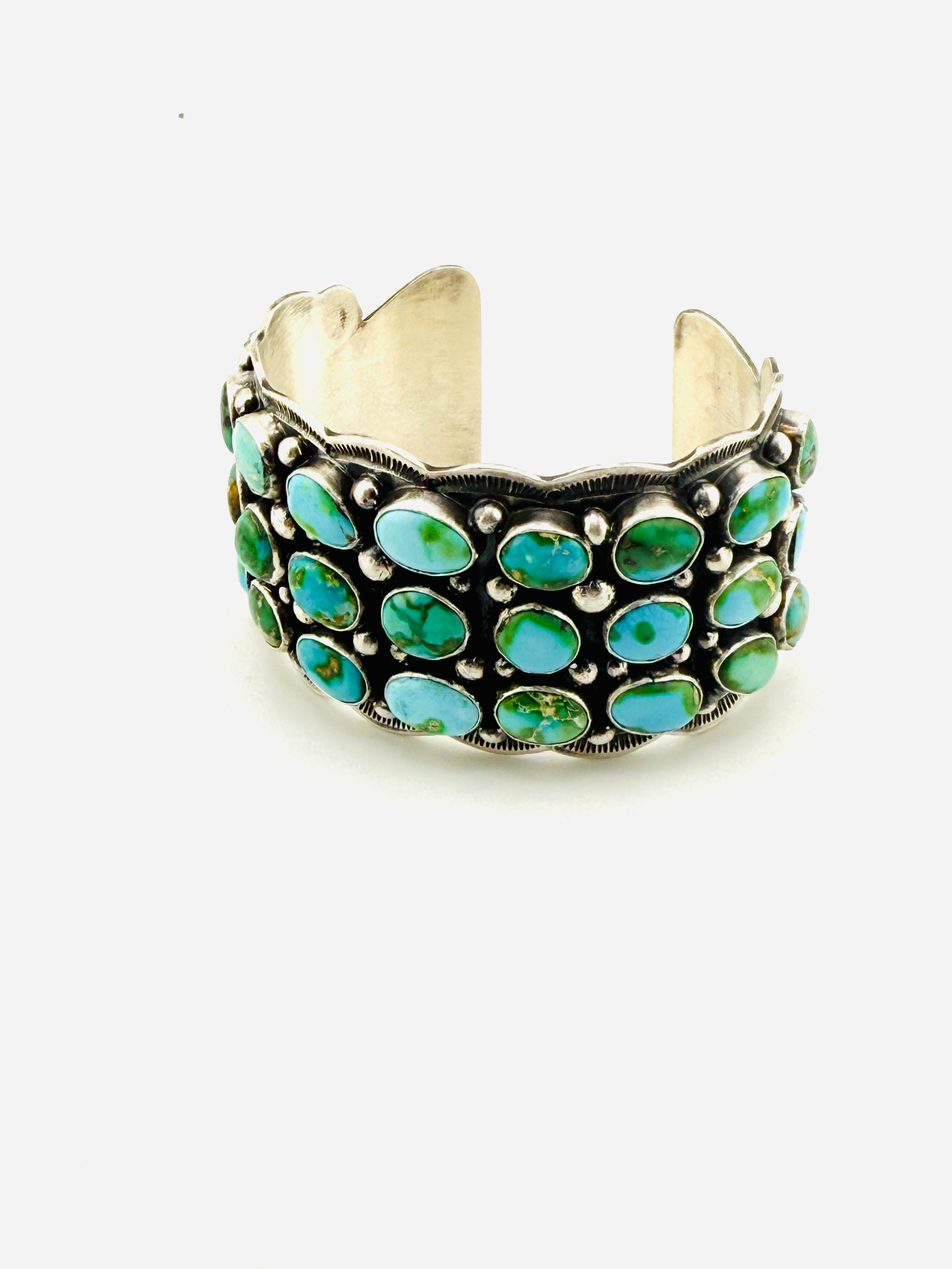 Silver cuff bracelet with turquoise stones on a white background