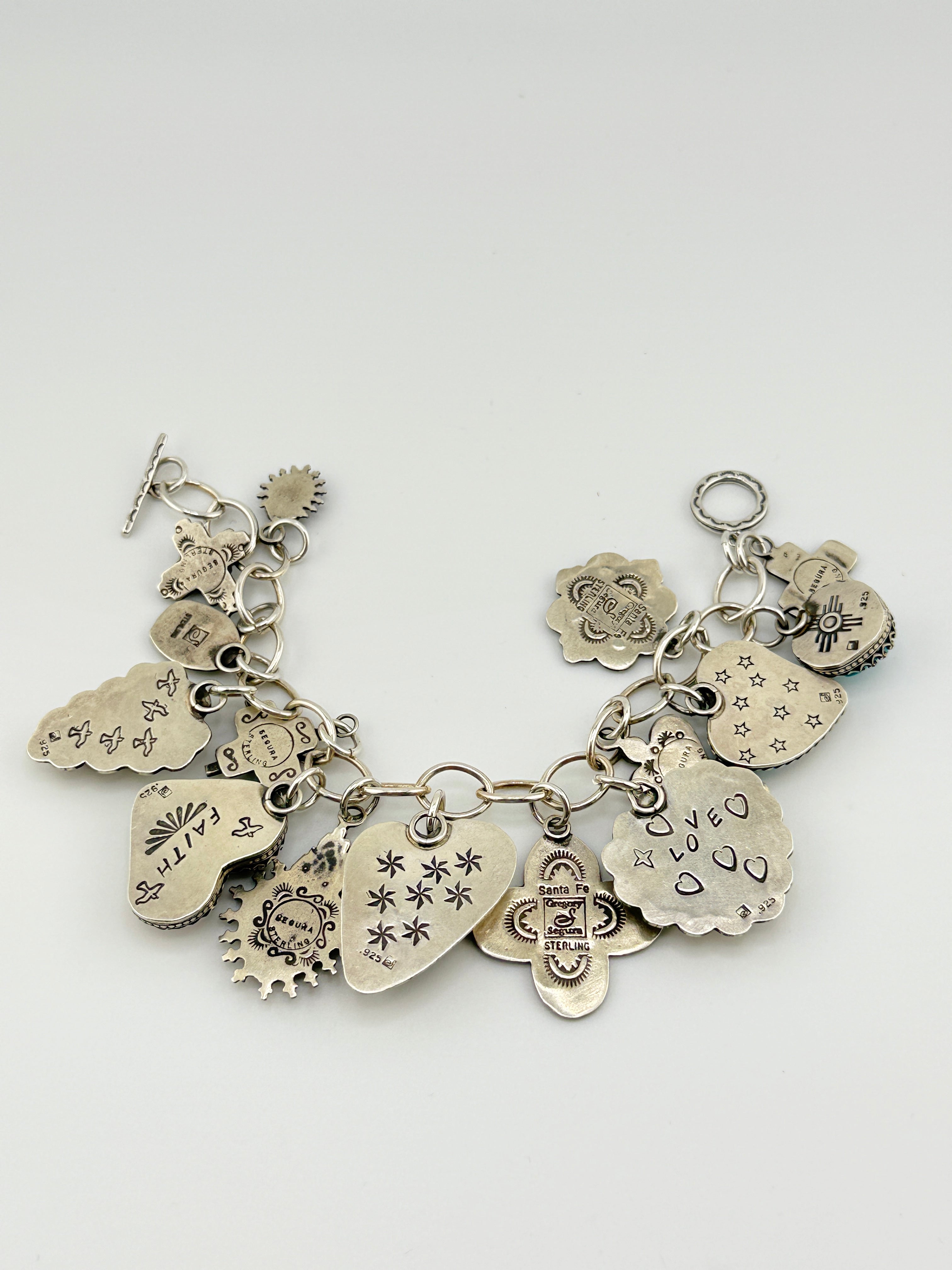 Silver charm bracelet with various charms on a white background