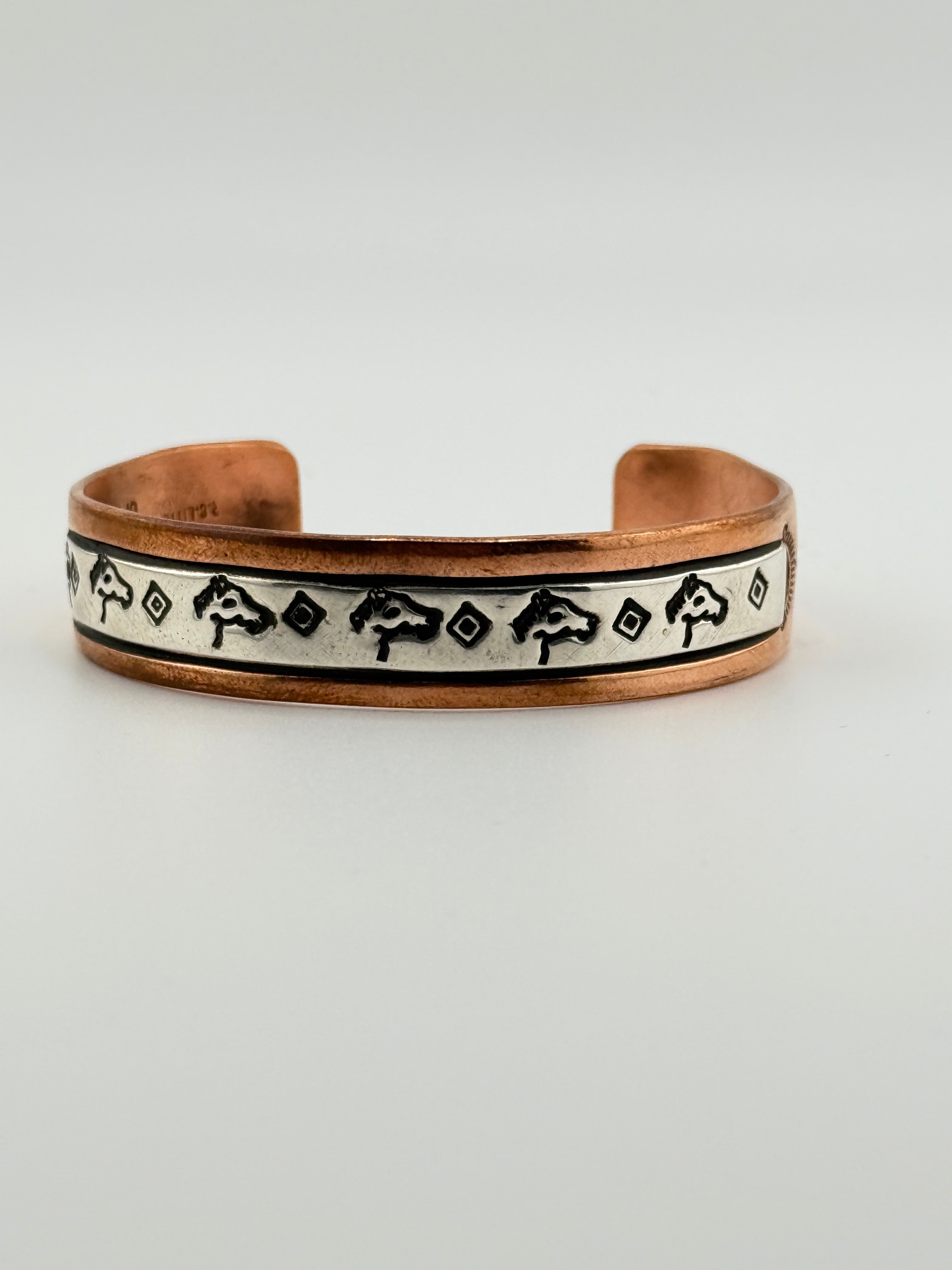 Copper bracelet with black and white pattern on a light gray background