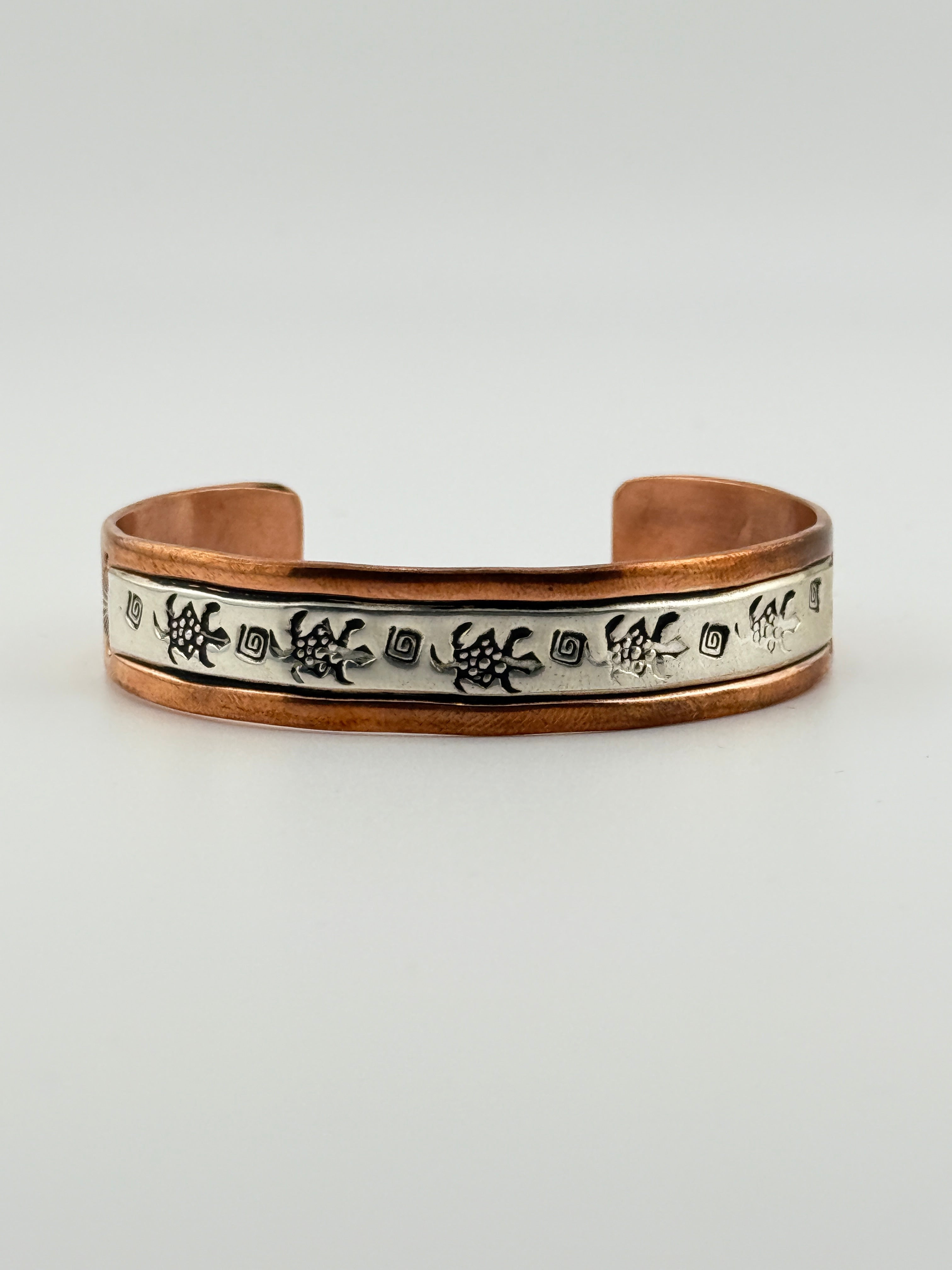 Copper bracelet with engraved design on a light gray background