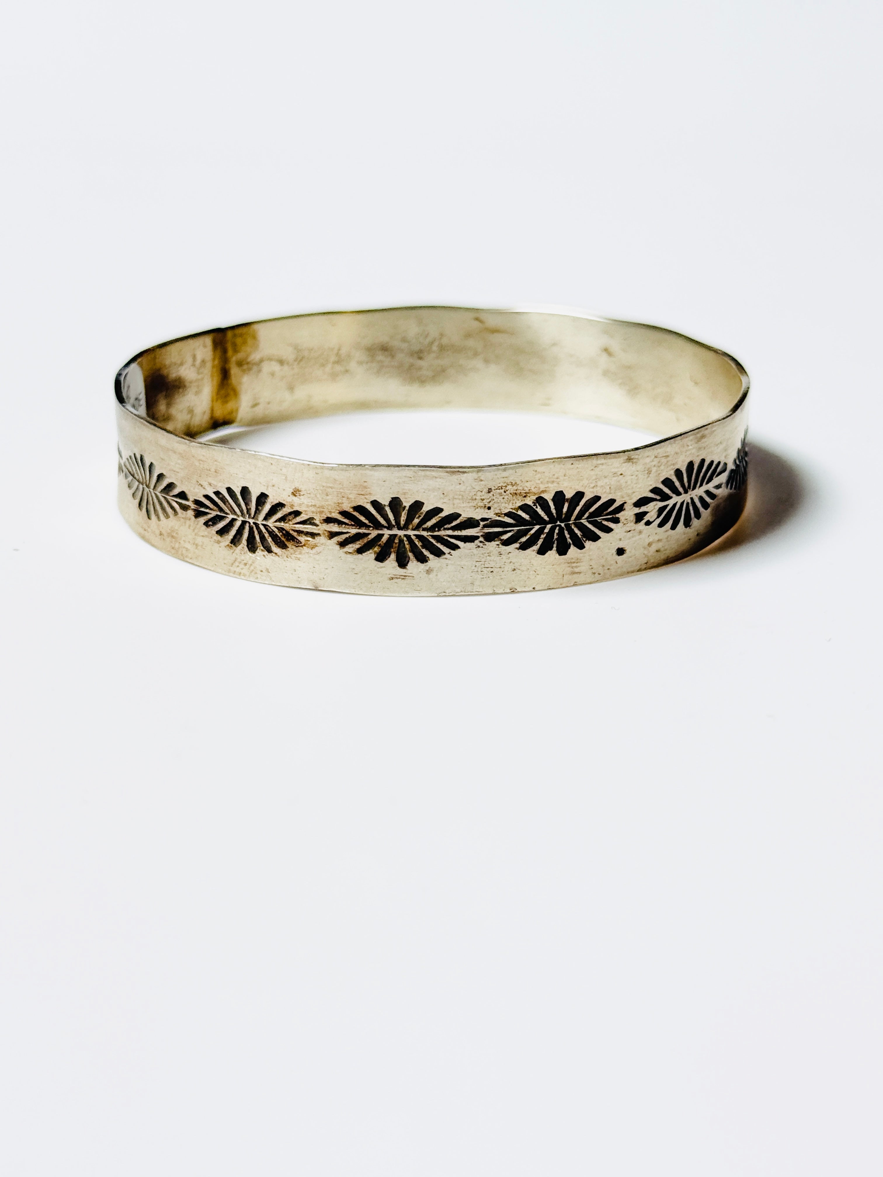 Silver bracelet with black floral patterns on a white background