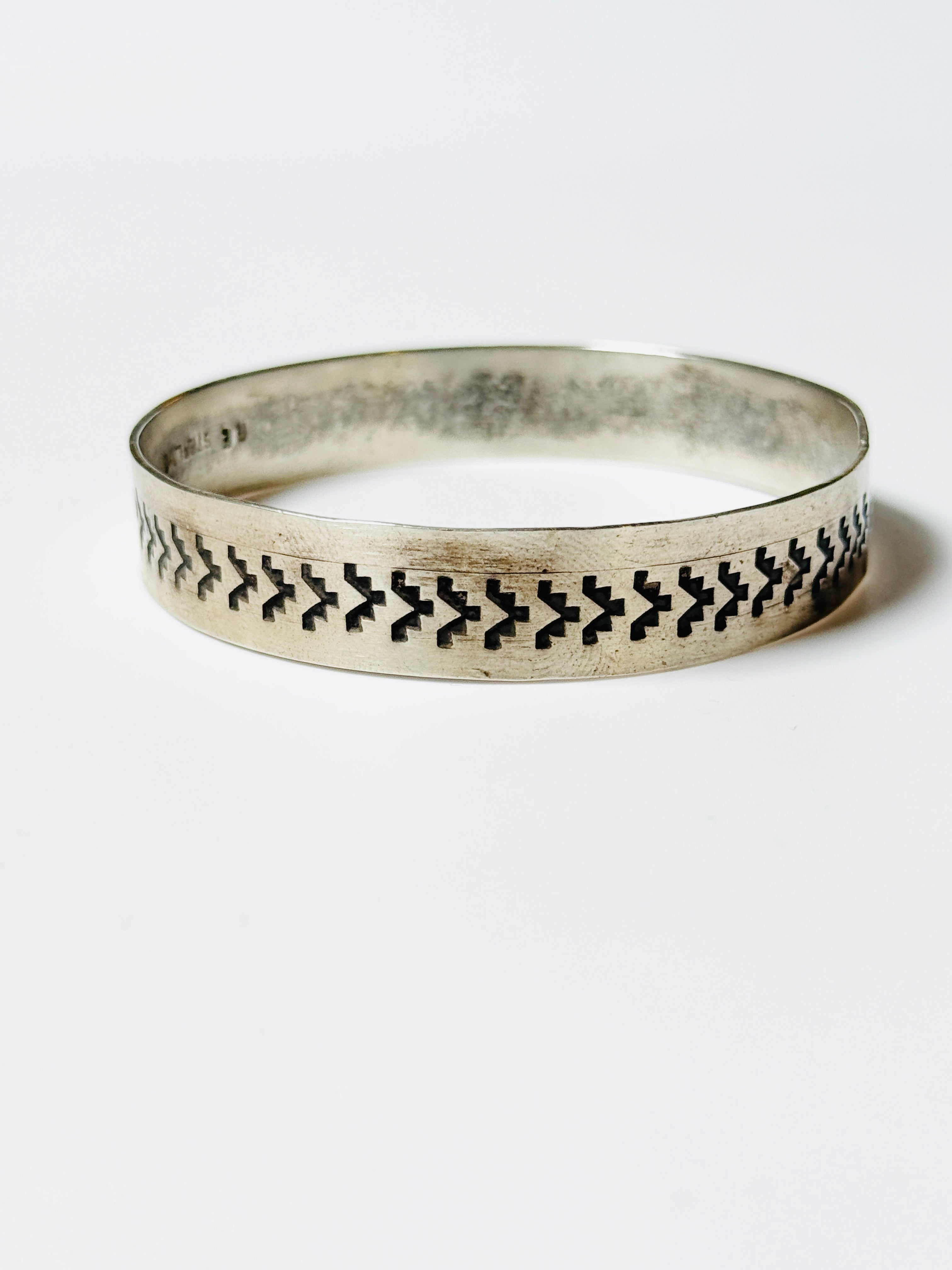 Silver bracelet with black pattern on a white background