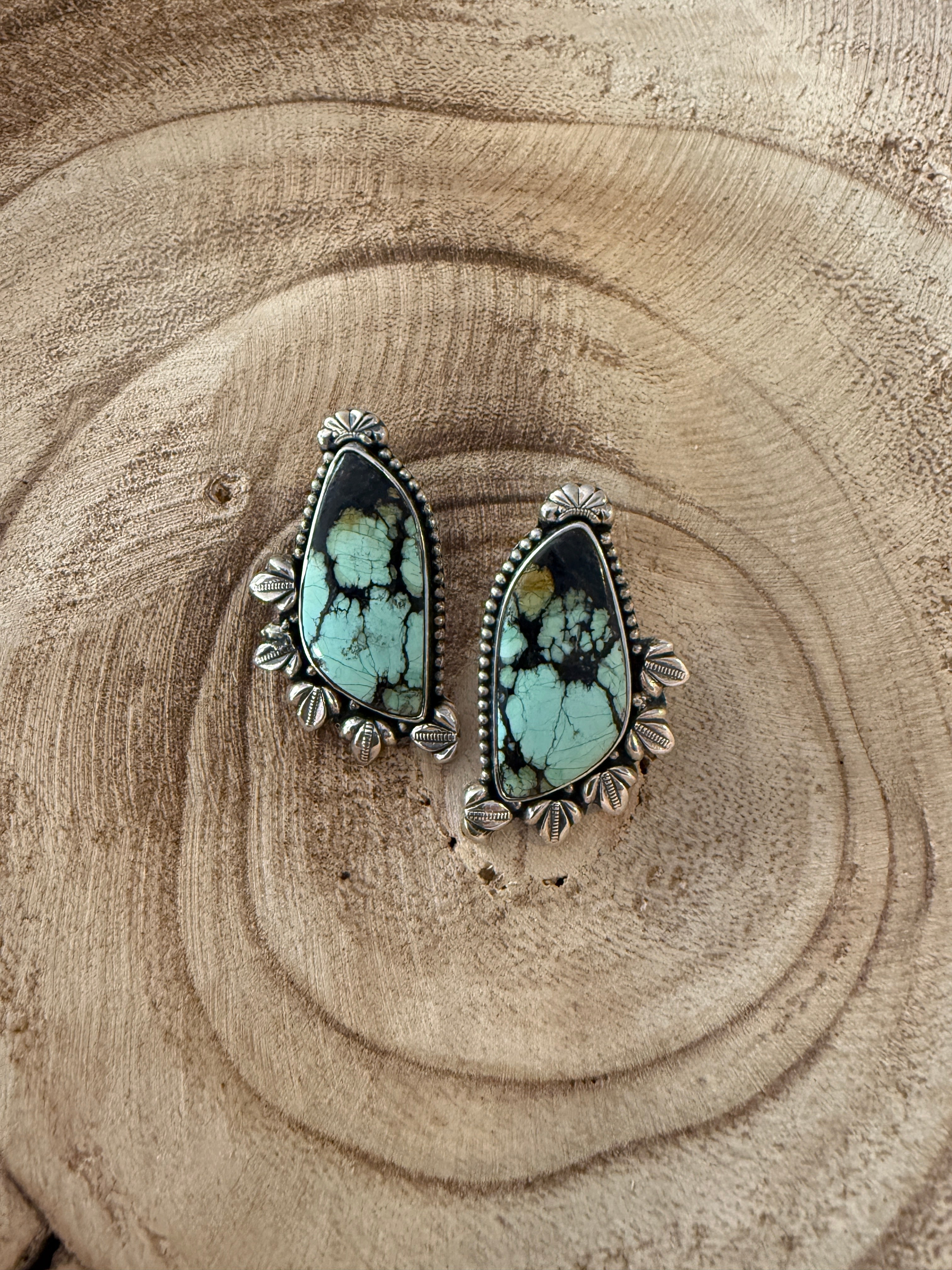 Turquoise teardrop earrings on a wooden surface