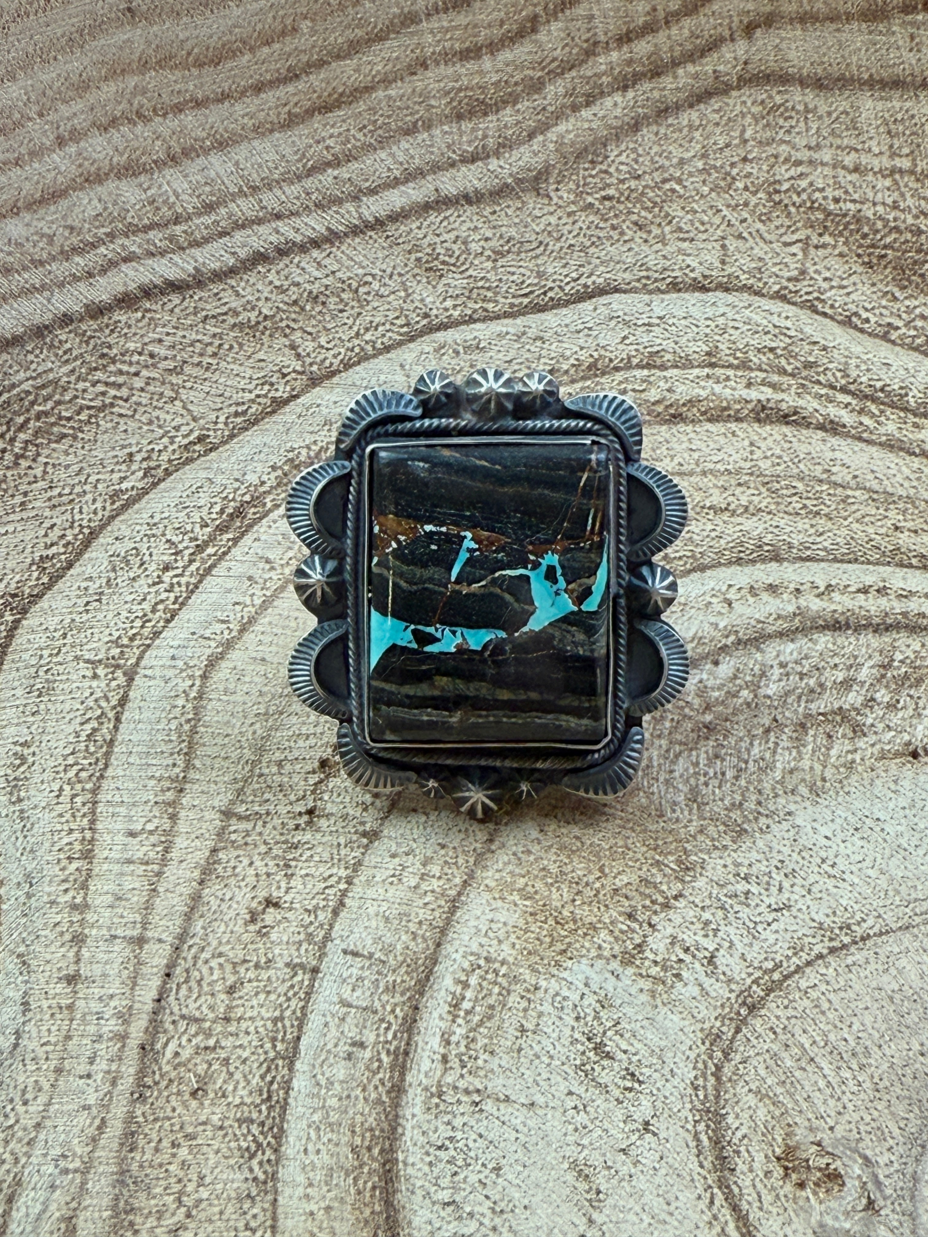 Jewelry piece with black and blue design on a textured surface