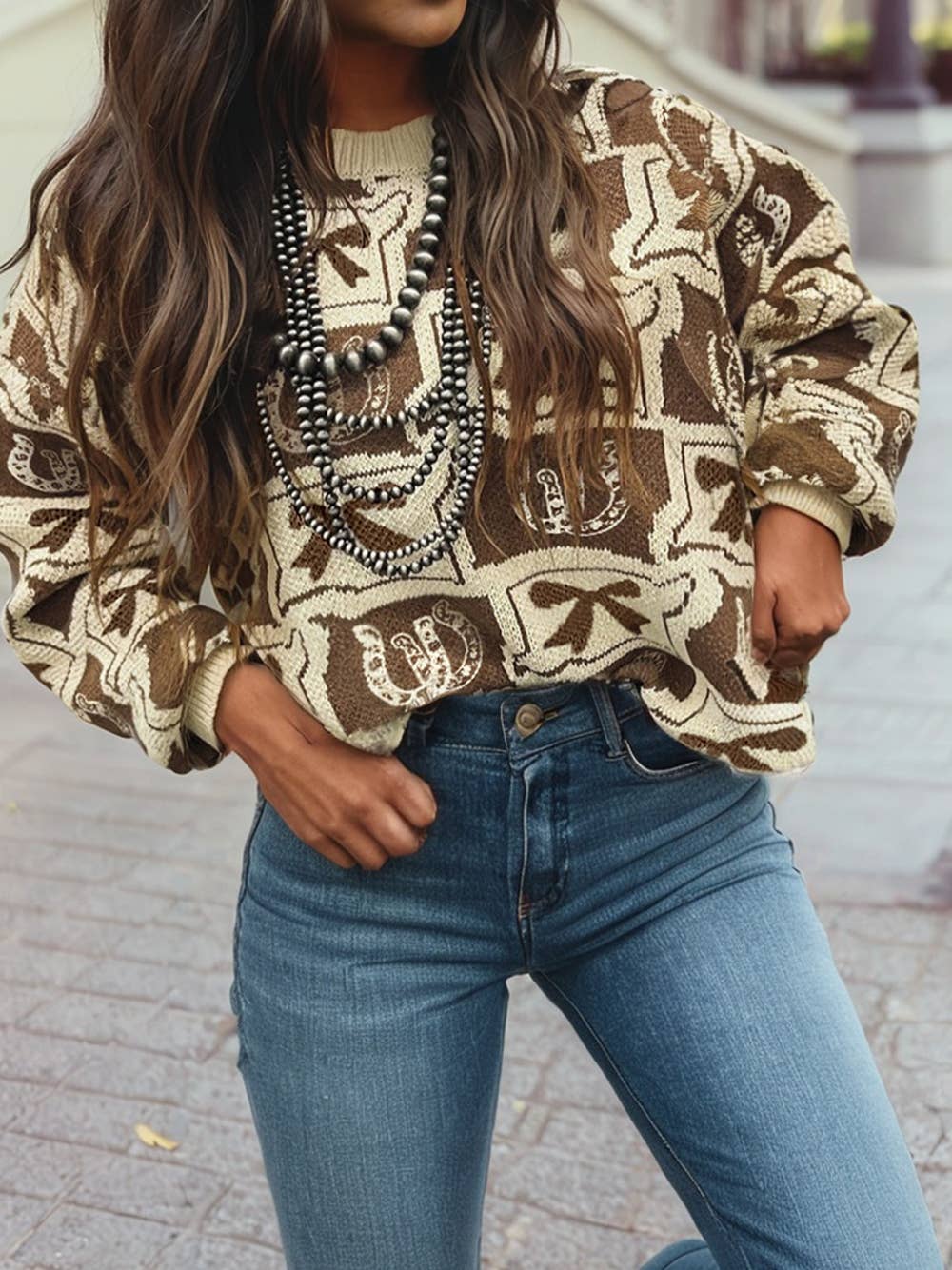Person wearing a patterned sweater and blue jeans on a blurred street background