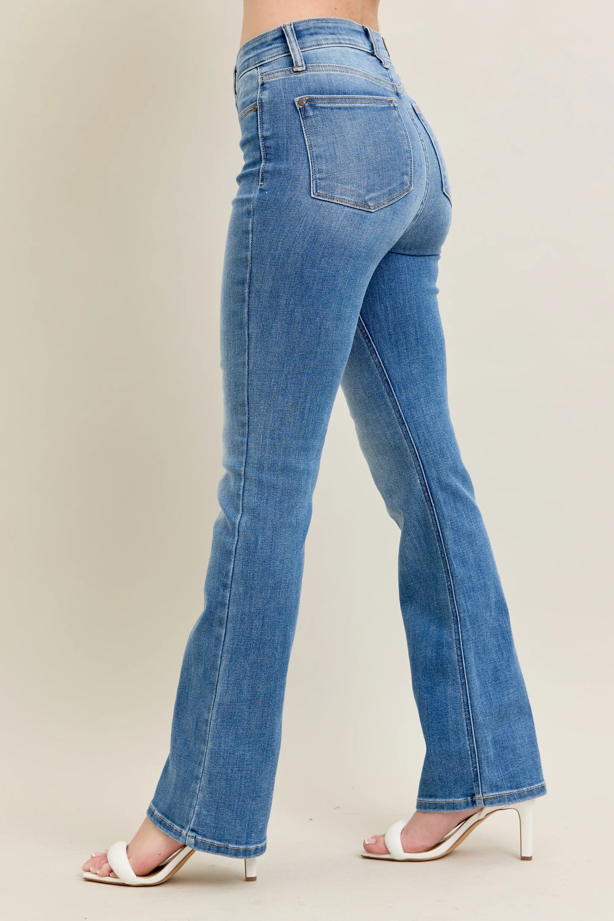 Blue jeans worn by a person on a plain background