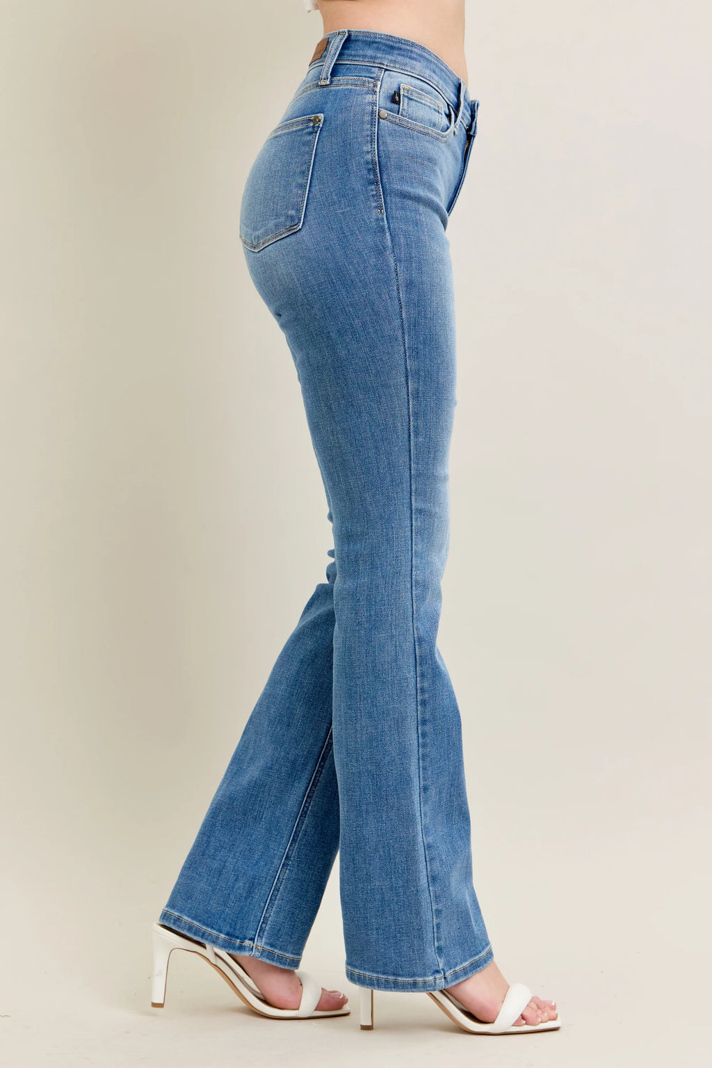 Blue jeans worn by a person on a plain background