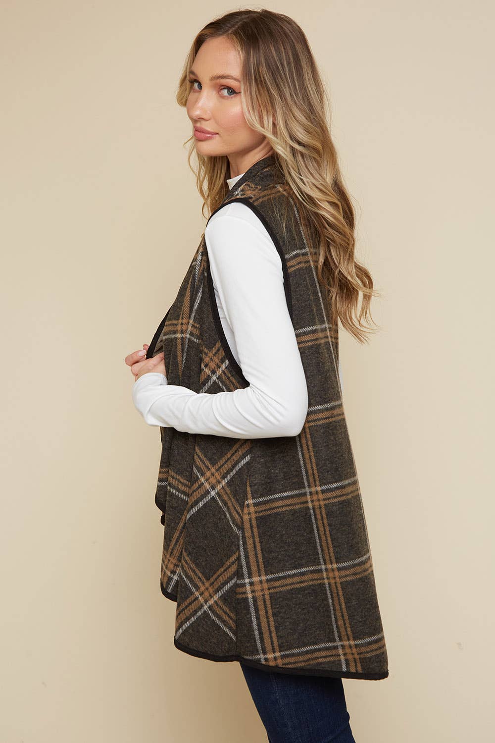 Woman wearing a plaid vest over a white shirt against a beige background