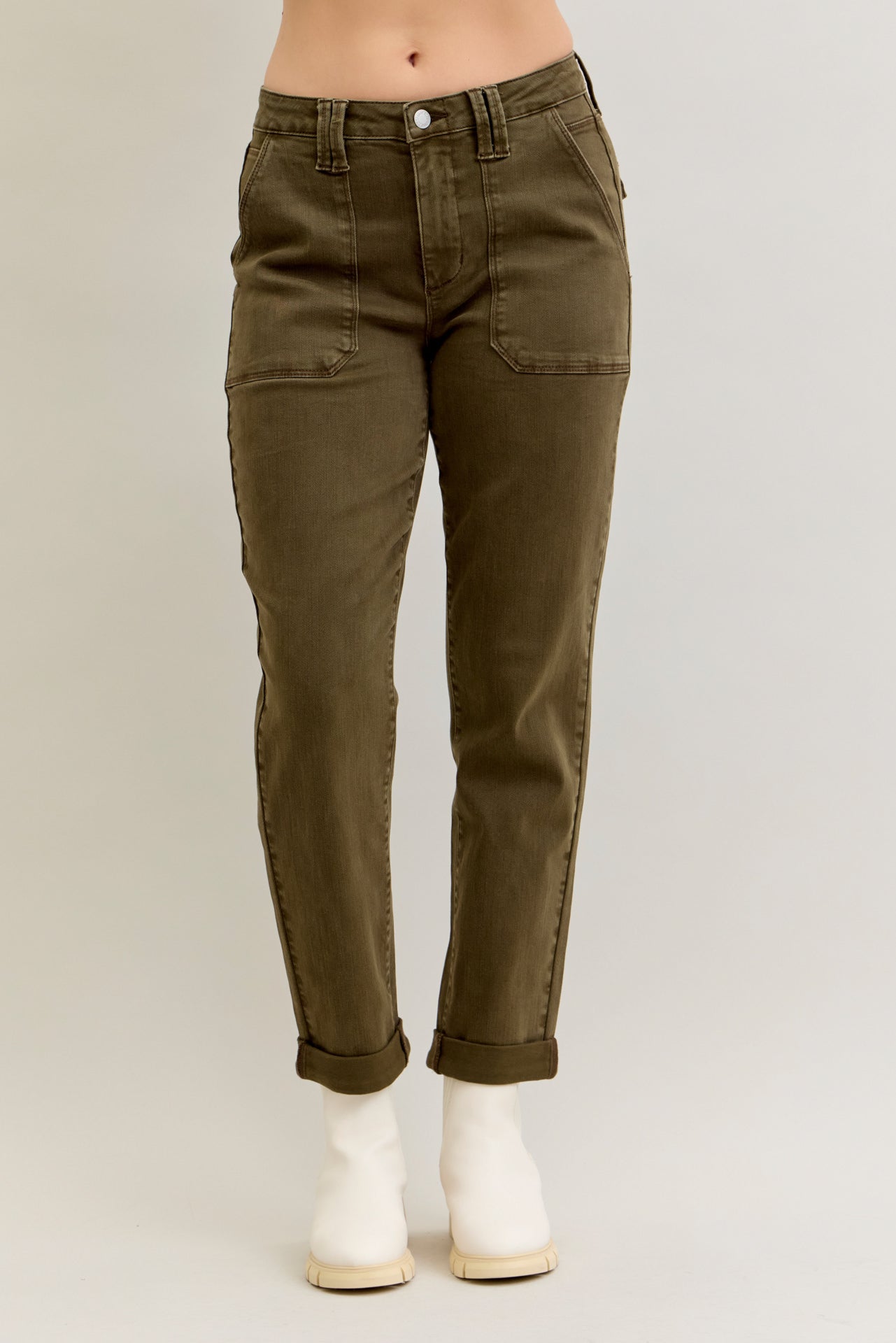 Olive green pants worn by a person on a plain background