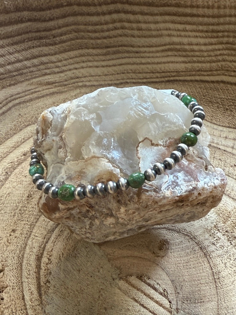 Bracelet with green and silver beads on a rock