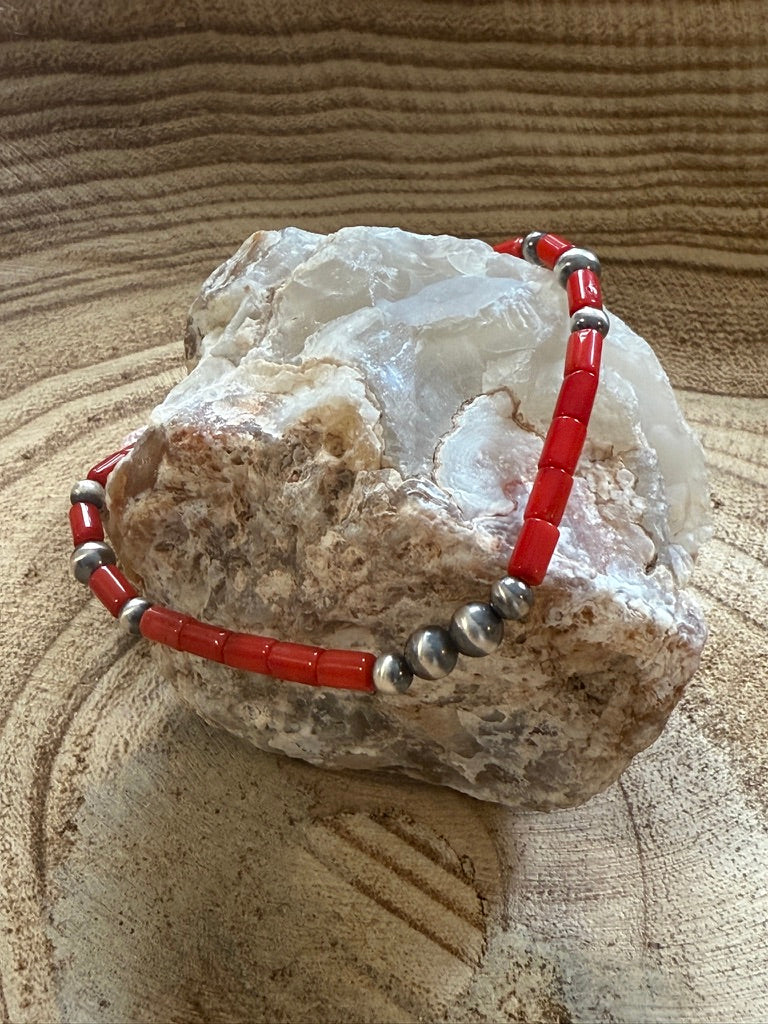 Bracelet with red and silver beads on a rock