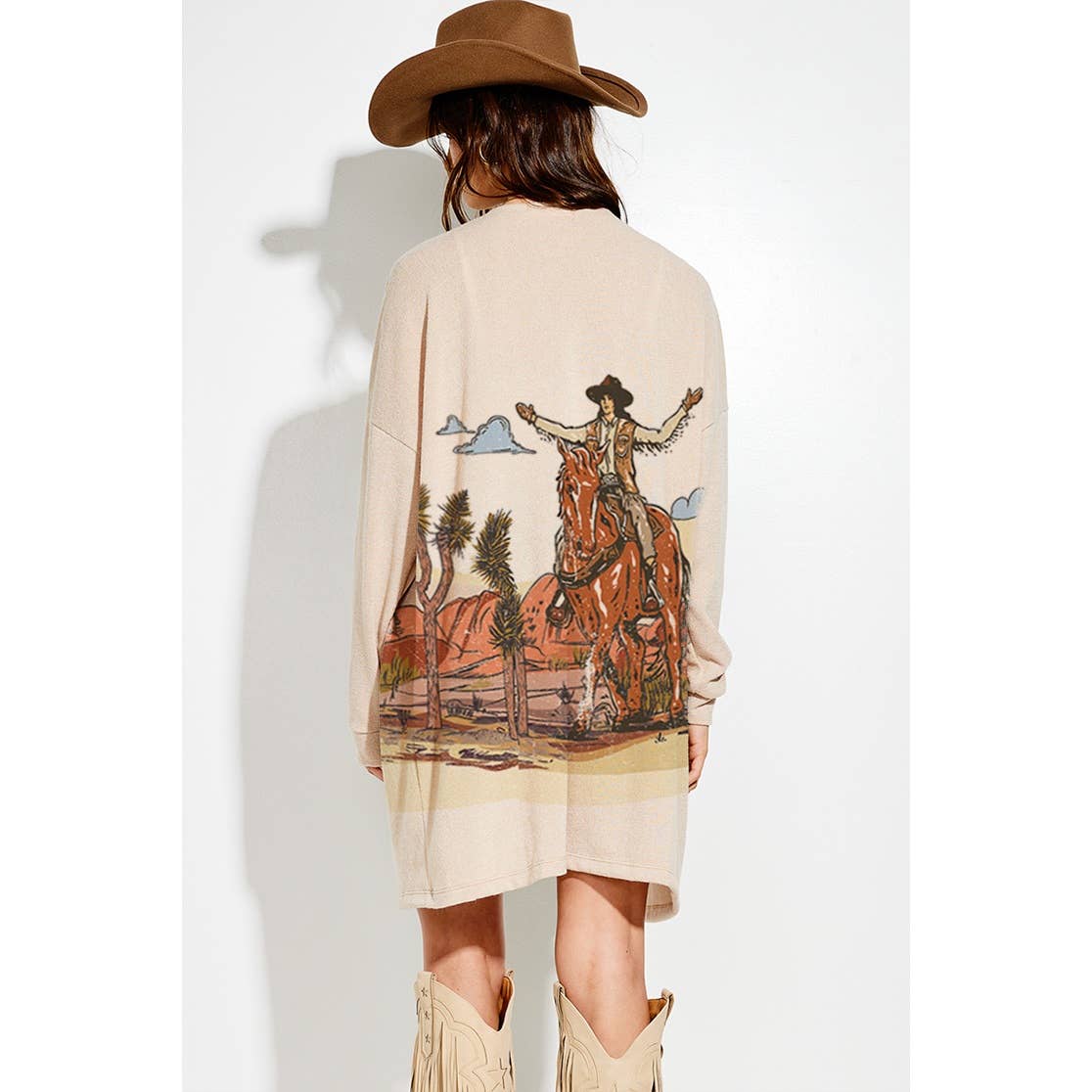 Person wearing a beige dress with a cowboy graphic on the back, standing against a white background.