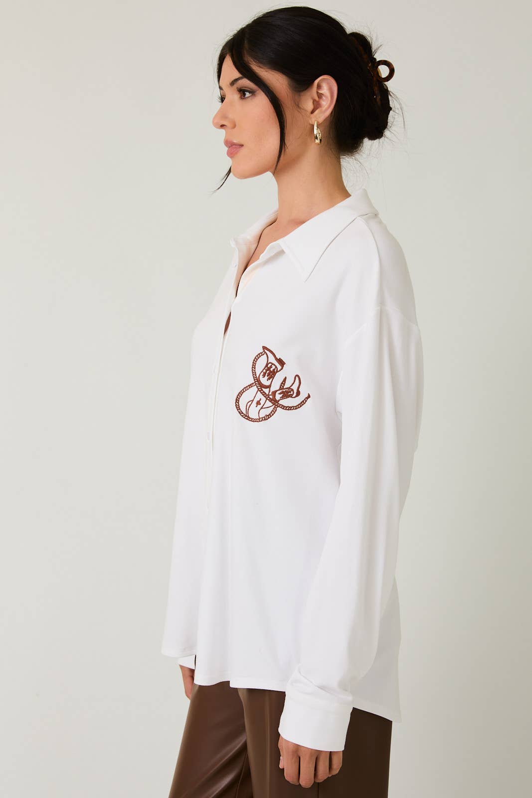 Woman wearing a white blouse with a red design on a plain background