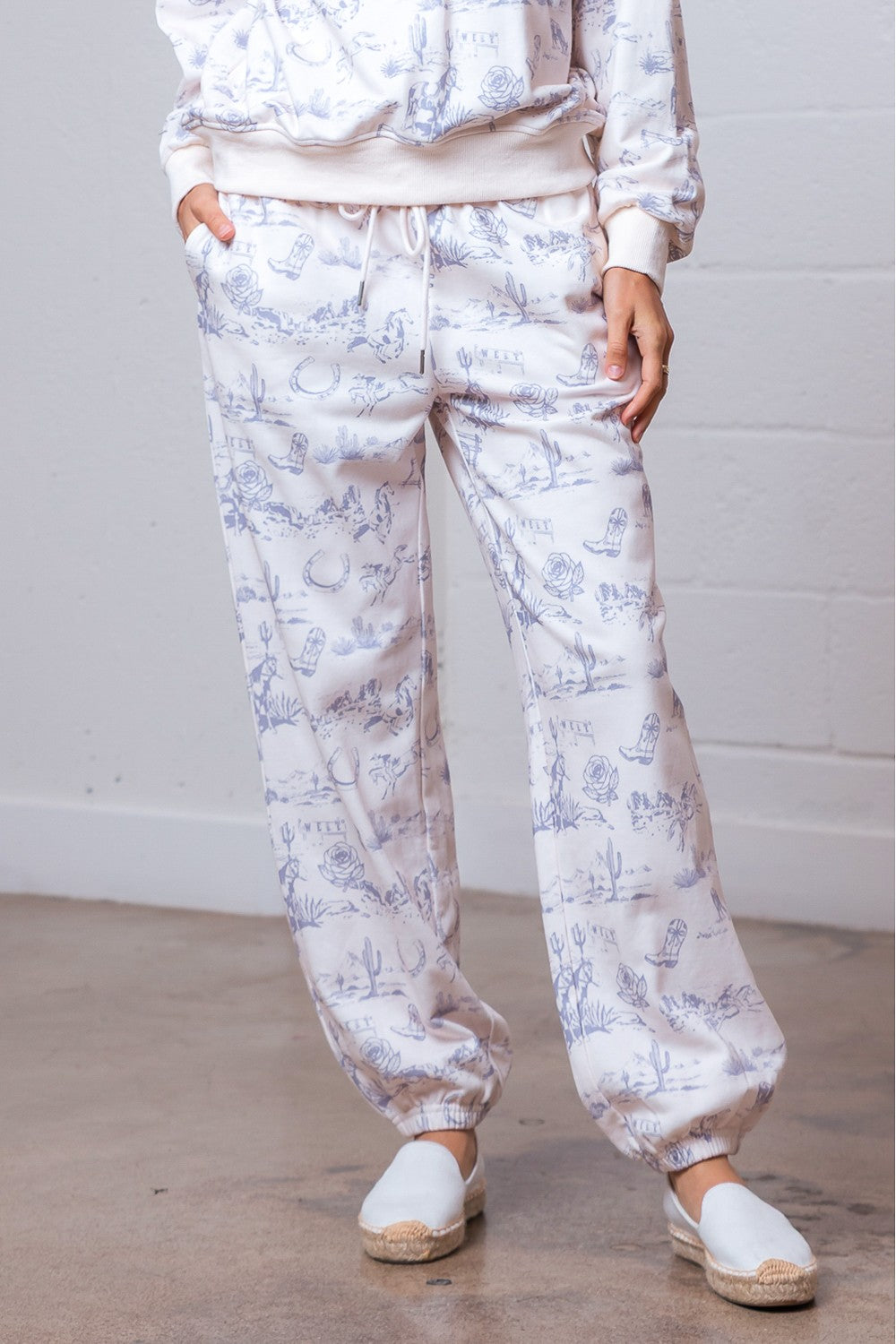 Person wearing a floral pajama set with white slippers on a wooden floor.