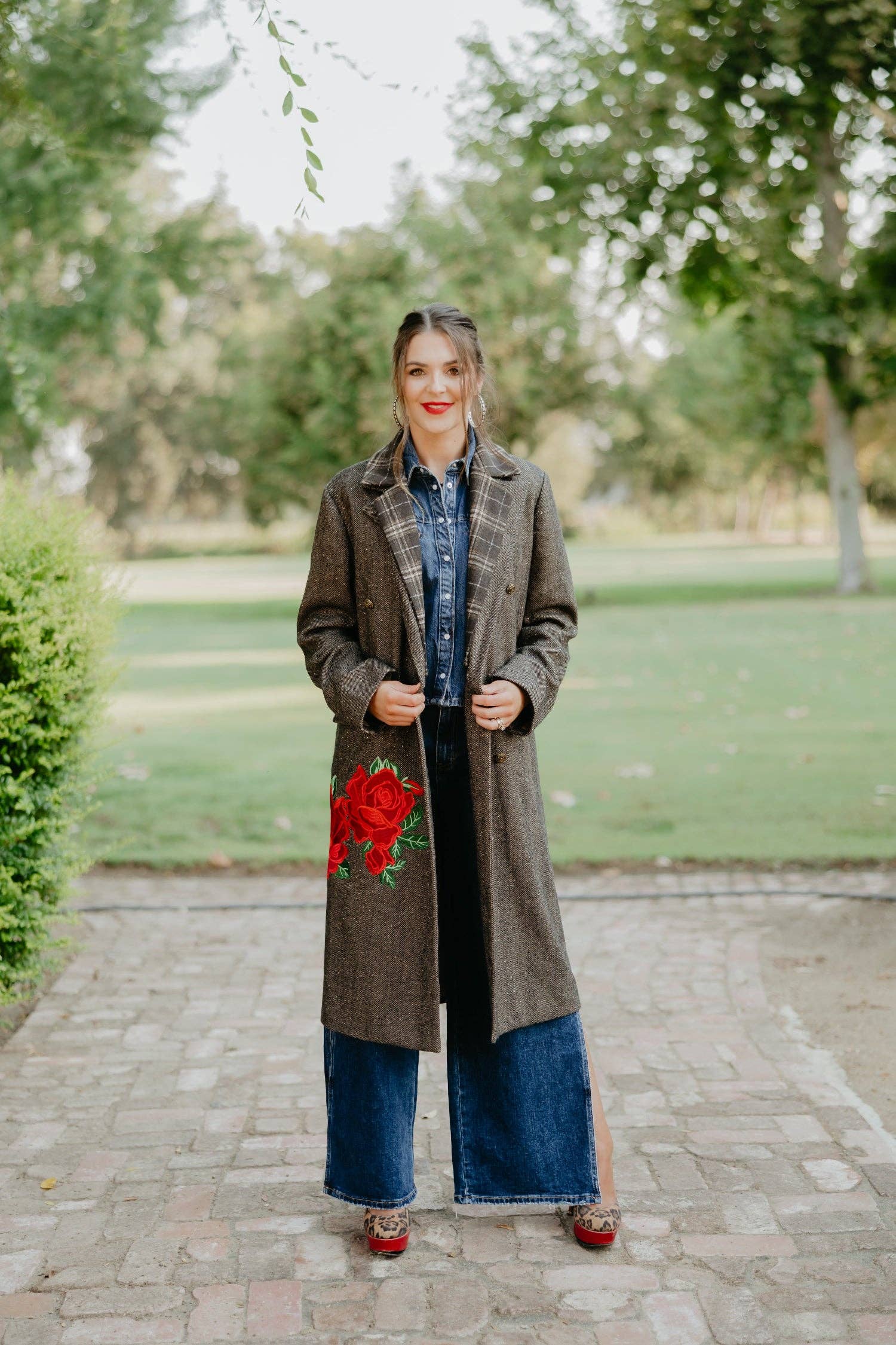 Woman wearing a long coat with a floral design in an outdoor setting