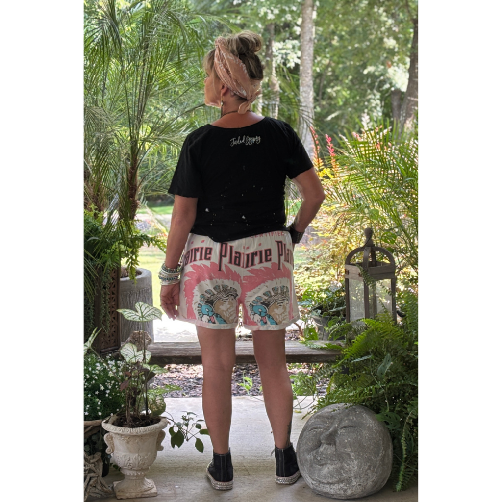Person wearing a black t-shirt and pink shorts with graphics in a garden setting