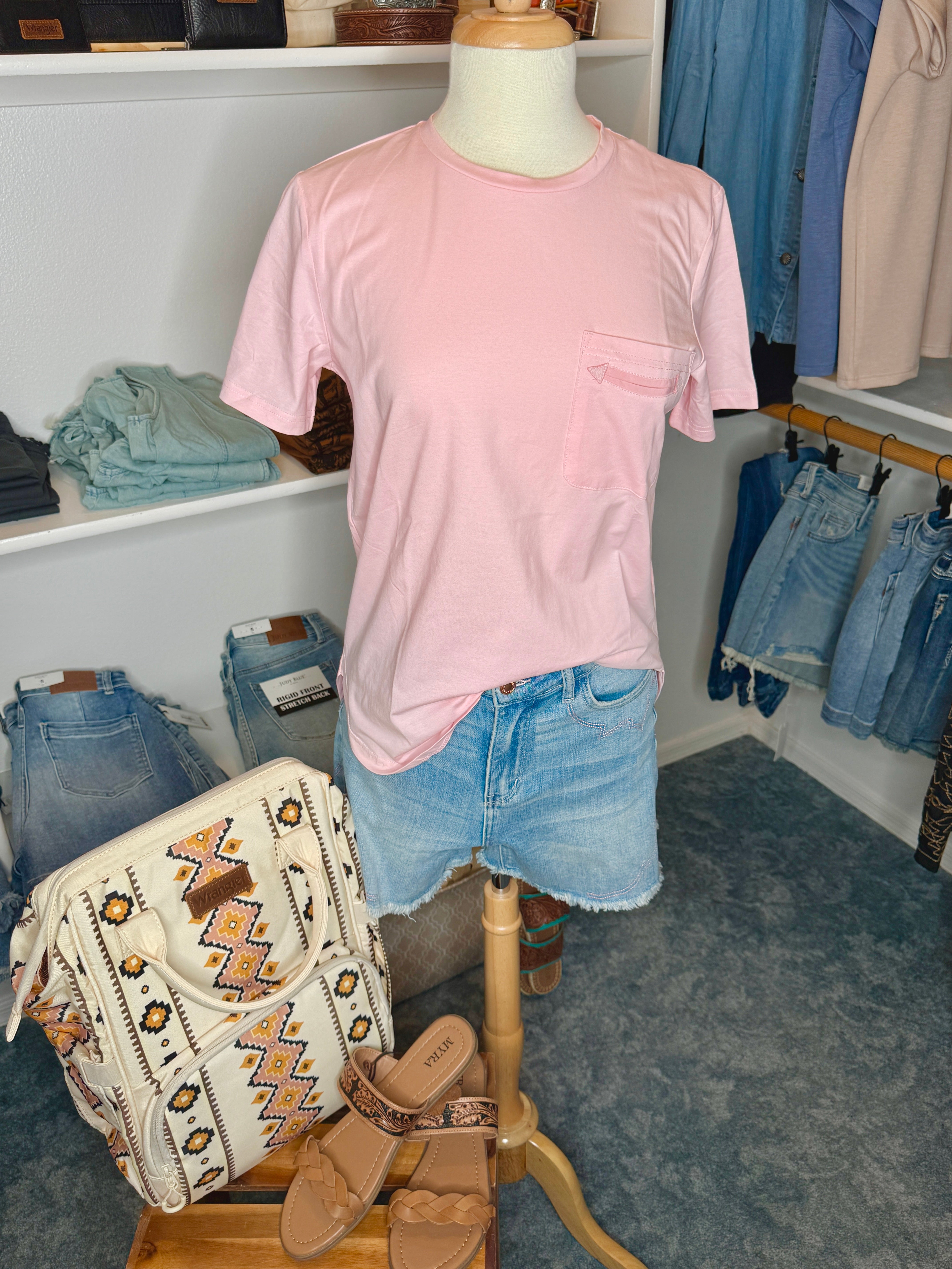Mannequin wearing a pink t-shirt and denim shorts with a backpack and shoes in the foreground.