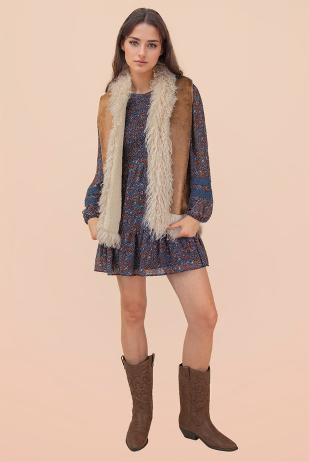 Woman wearing a patterned dress with a fur vest and brown boots on a beige background