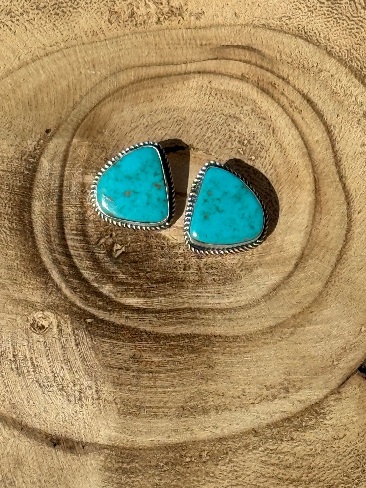 Turquoise stone earrings on a wooden surface