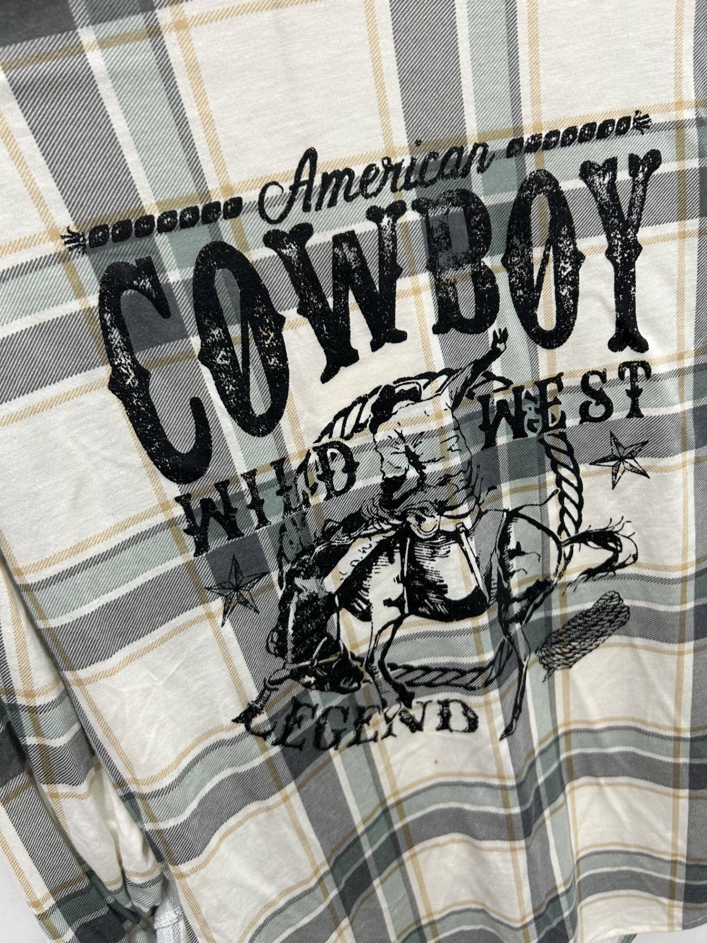 Plaid fabric with 'American Cowboy' text and graphic design.