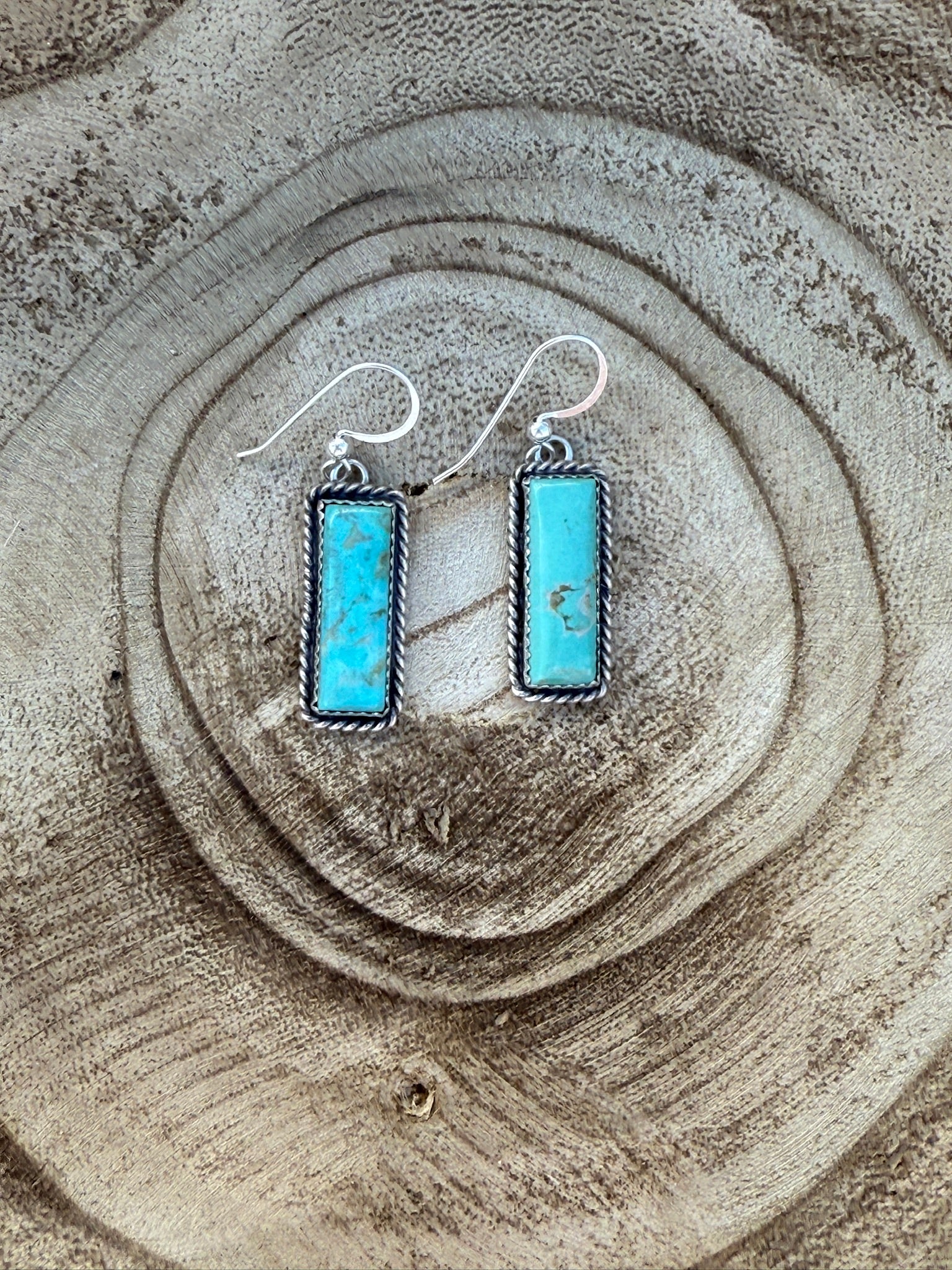 Turquoise earrings on a textured stone surface