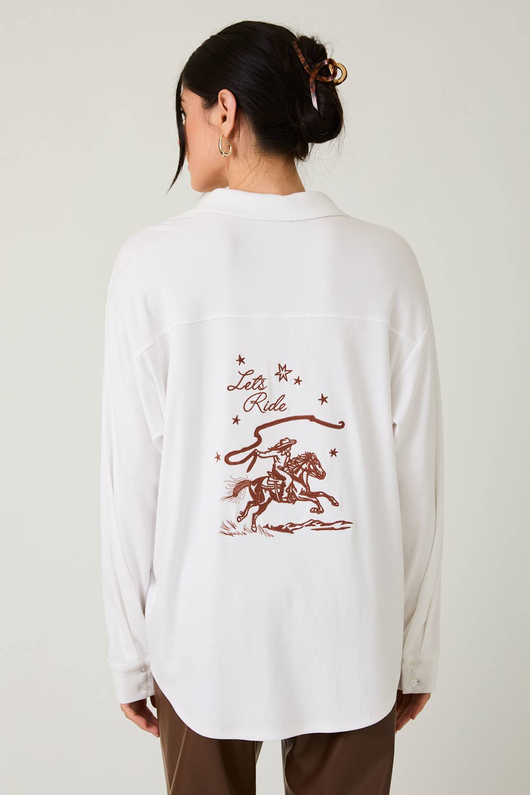 Person wearing a white shirt with a red graphic and text on the back, against a plain background