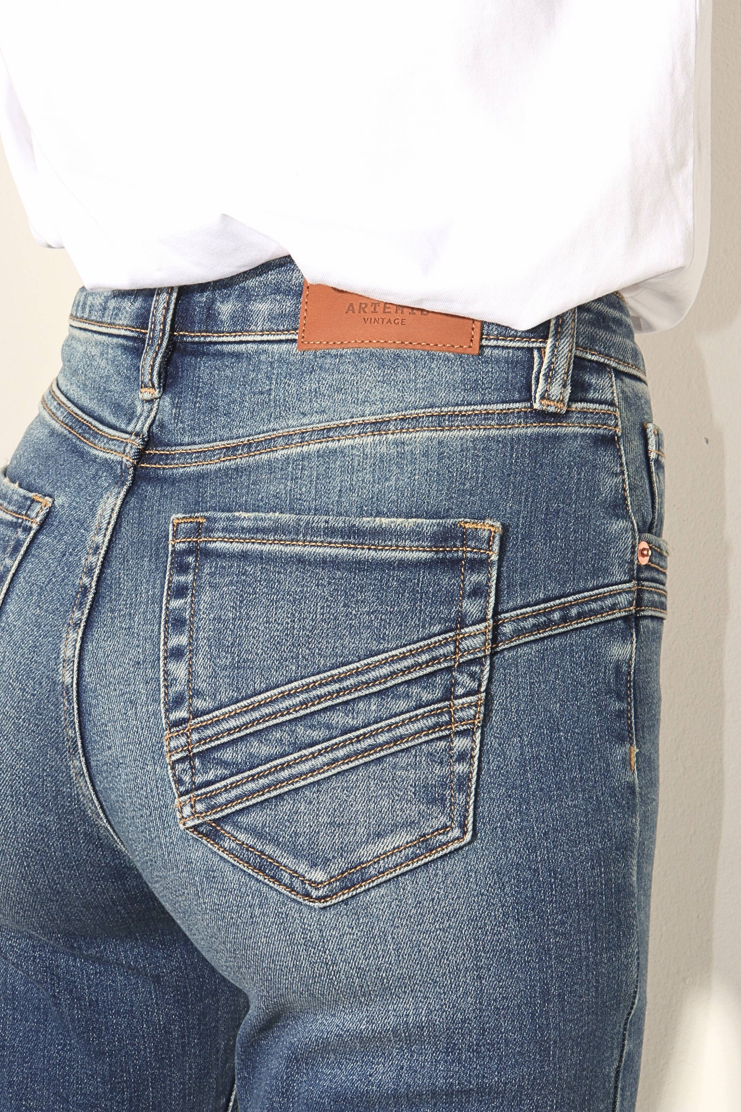 Close-up of blue jeans with a brand label on a plain background