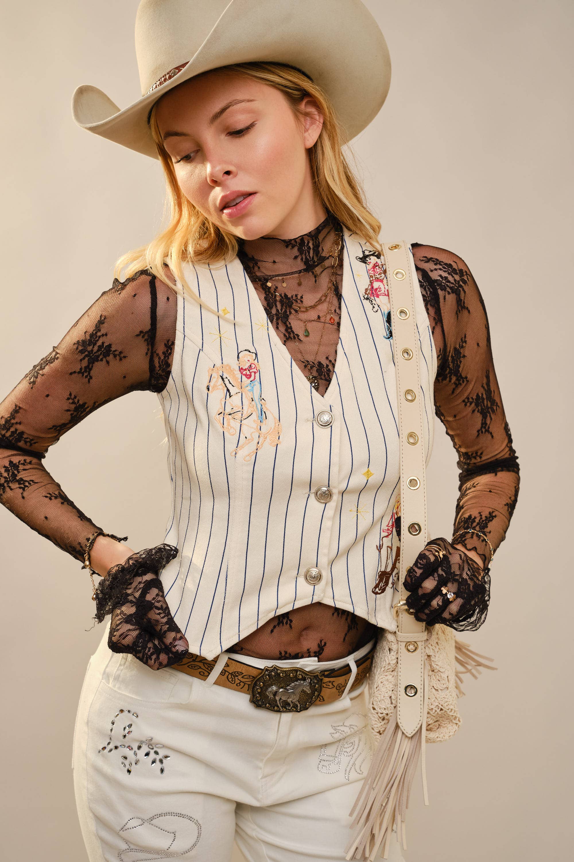 Person wearing a cowboy hat, pinstripe vest, and white pants with decorative elements on a plain background