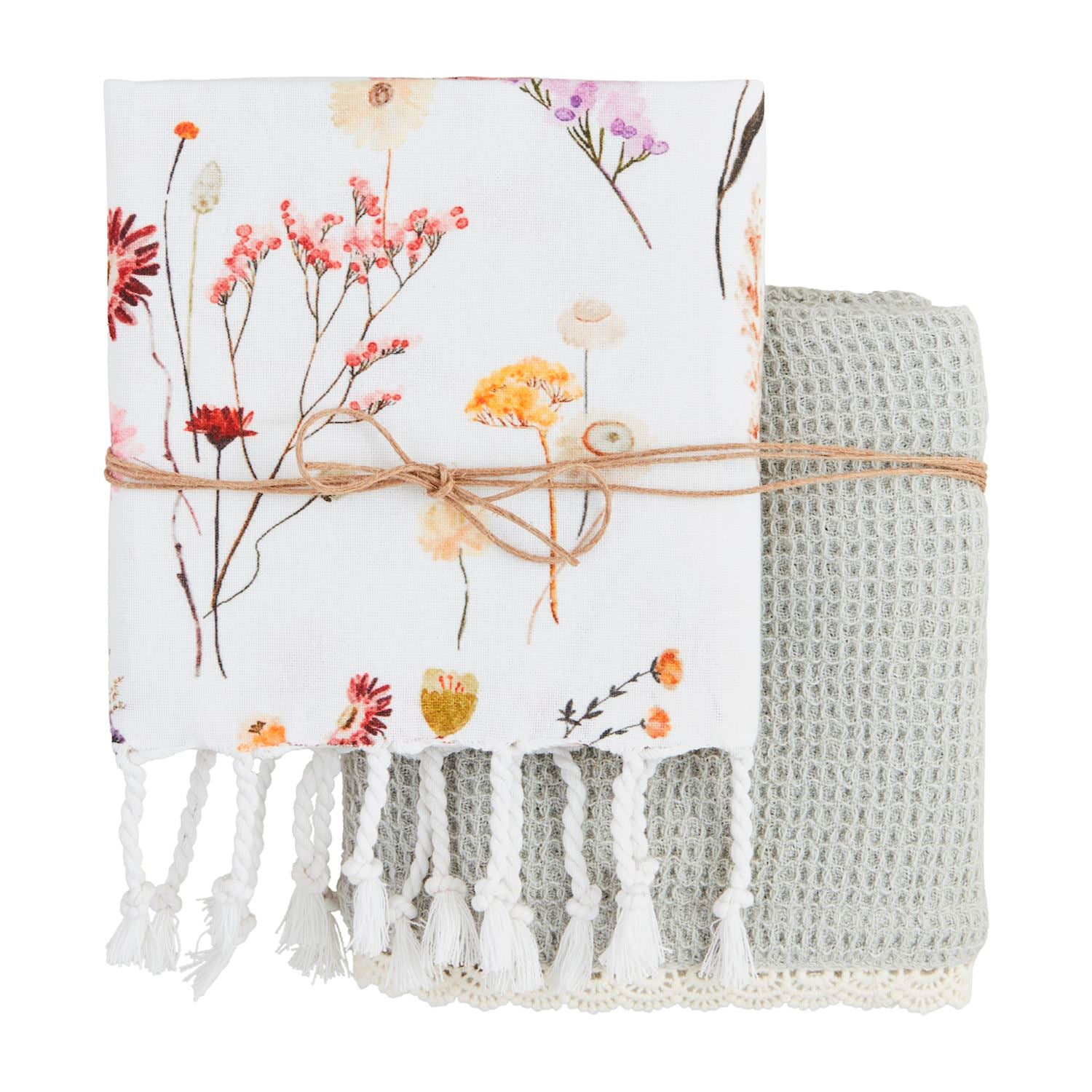 Floral-patterned blanket with tassels and a textured gray throw on a white background