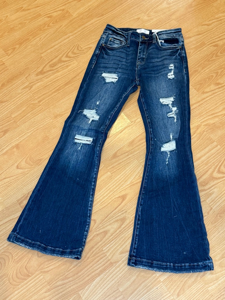 Pair of blue jeans with distressed details on a wooden floor.