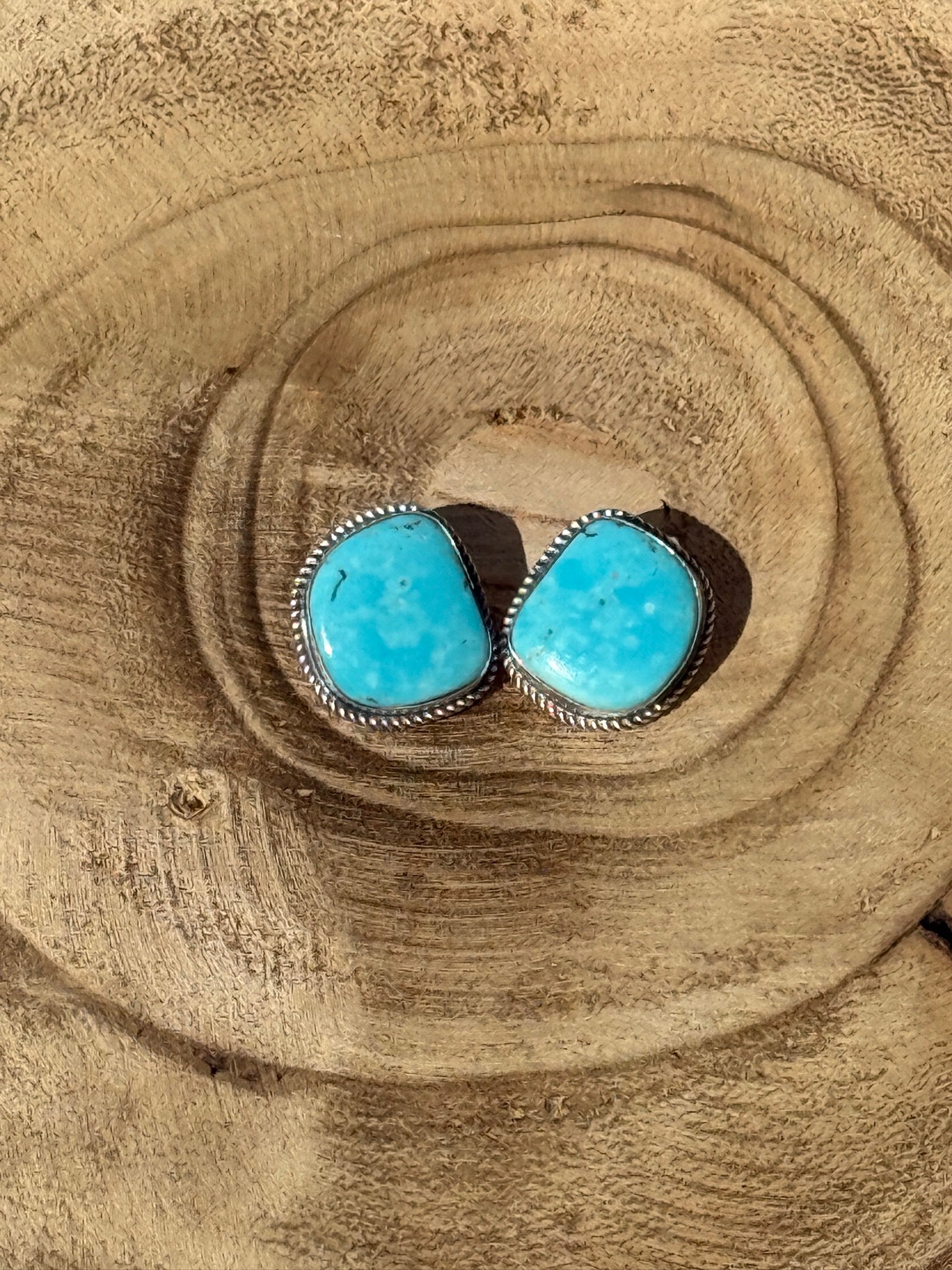 Turquoise stone earrings on a wooden surface
