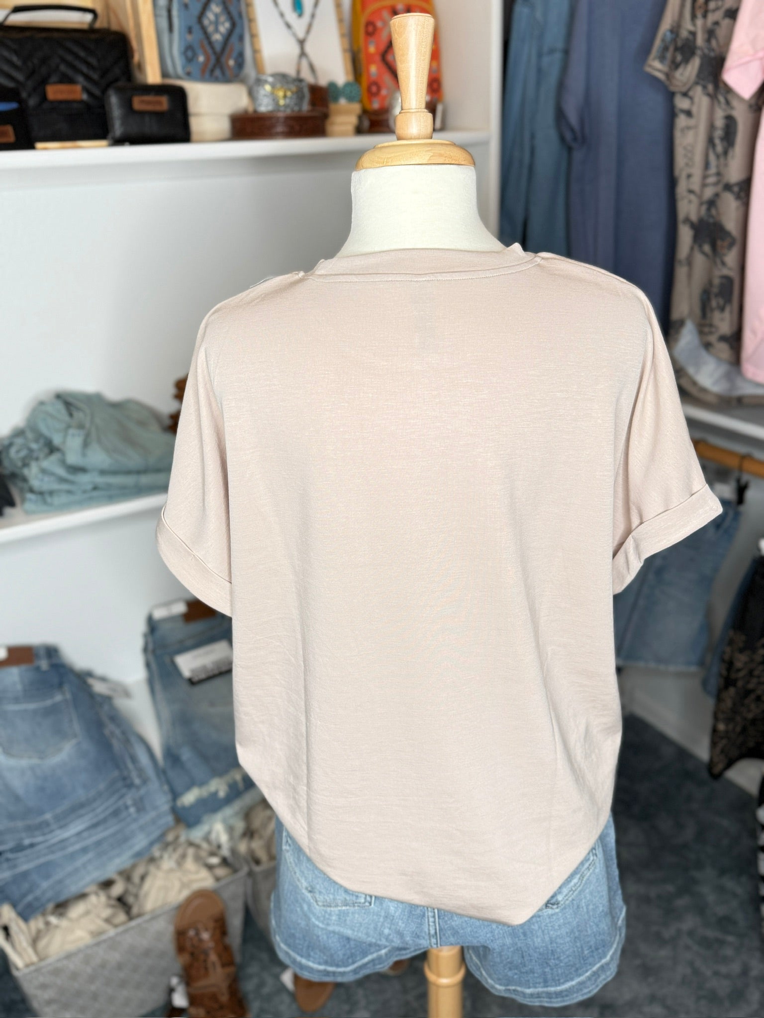 Beige t-shirt on a mannequin in a clothing store.