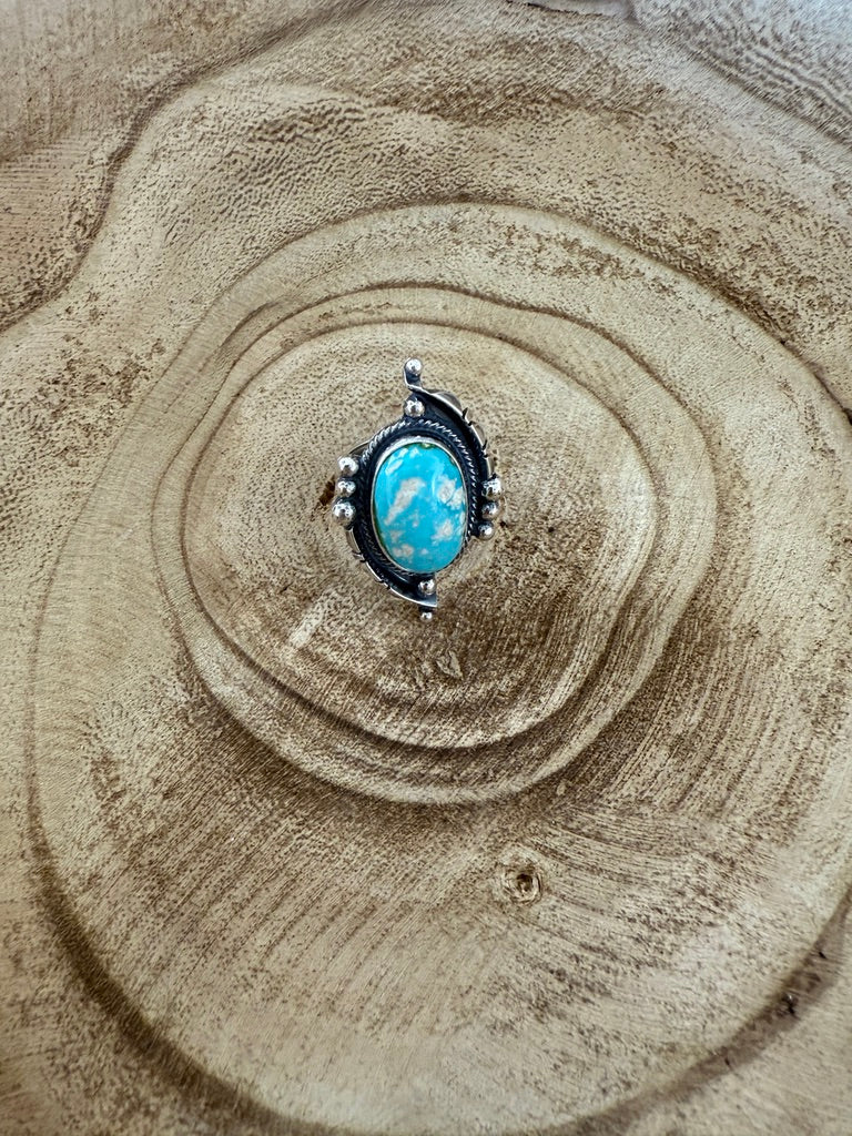 Turquoise stone ring on a textured sand surface