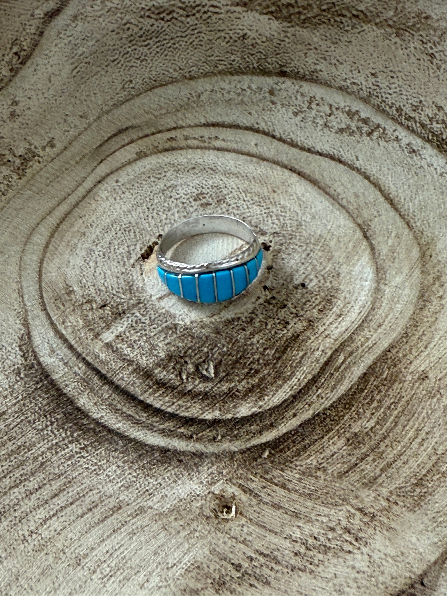 Silver ring with blue stone on sand